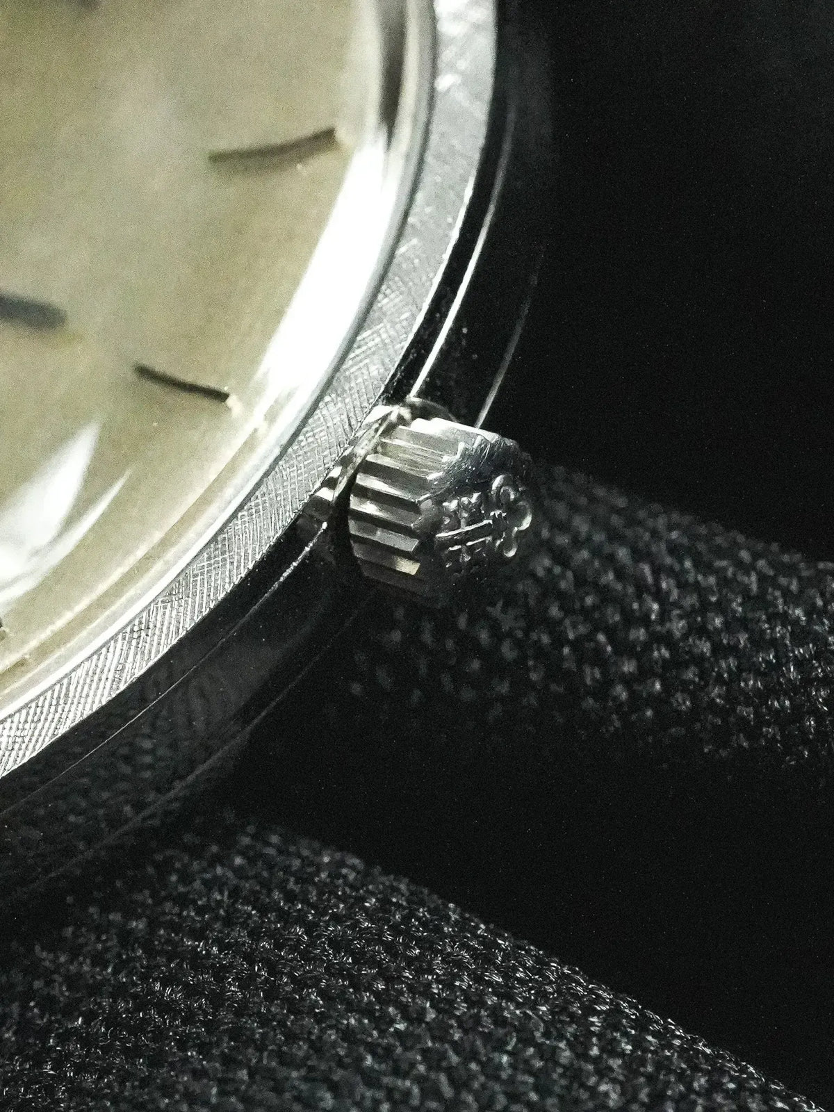 Vintage Rolex watch with fluted bezel and silver dial on dark fabric
