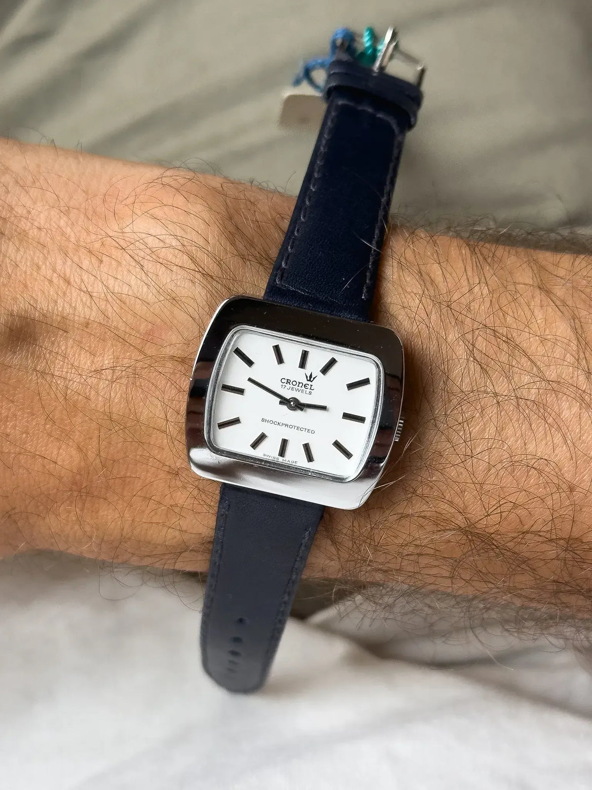 Cronel vintage watch with white dial, black markers, and navy leather strap on wrist