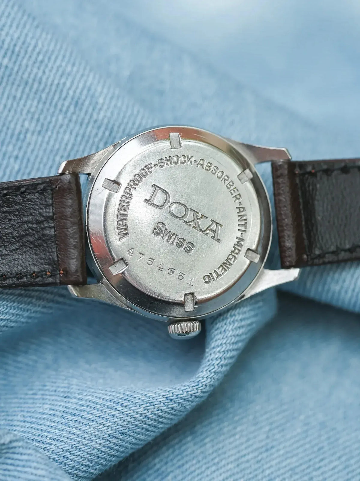 Doxa vintage watch back with engraved waterproof shock absorber details on denim