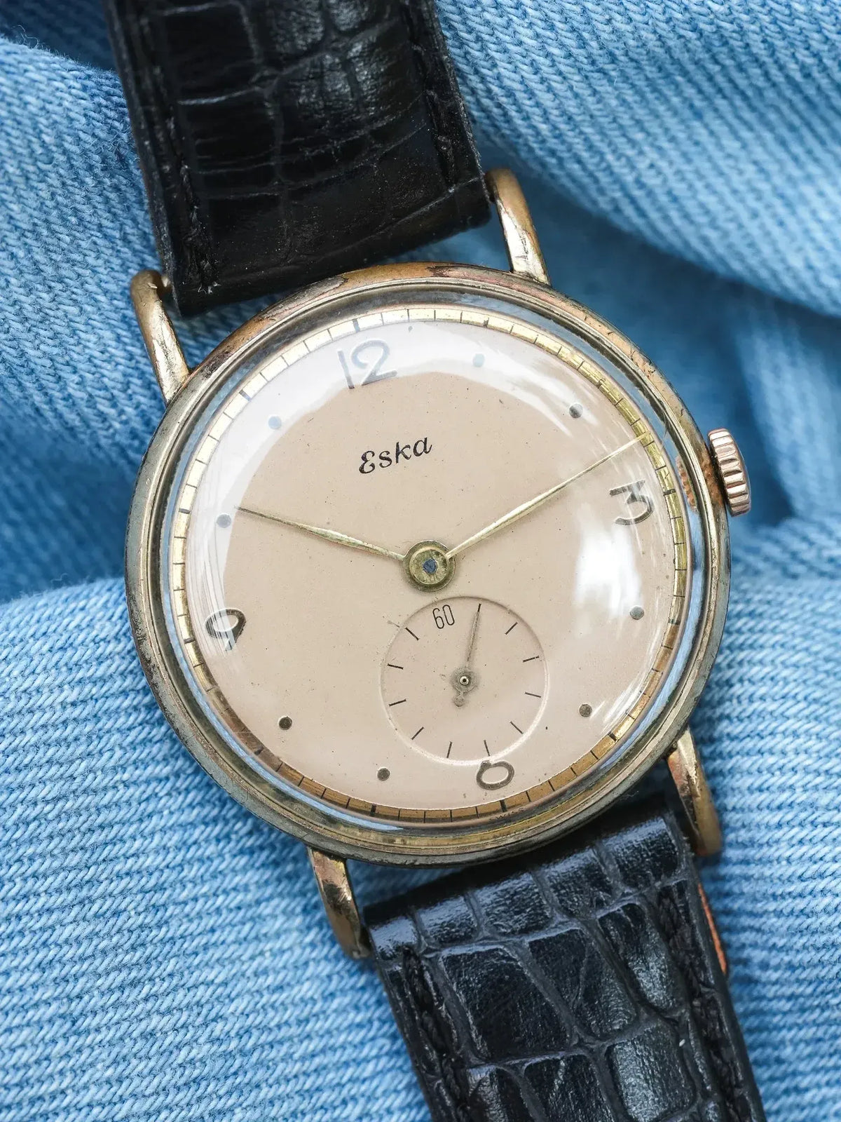 Vintage Eska watch with cream dial, gold case, black crocodile strap on denim