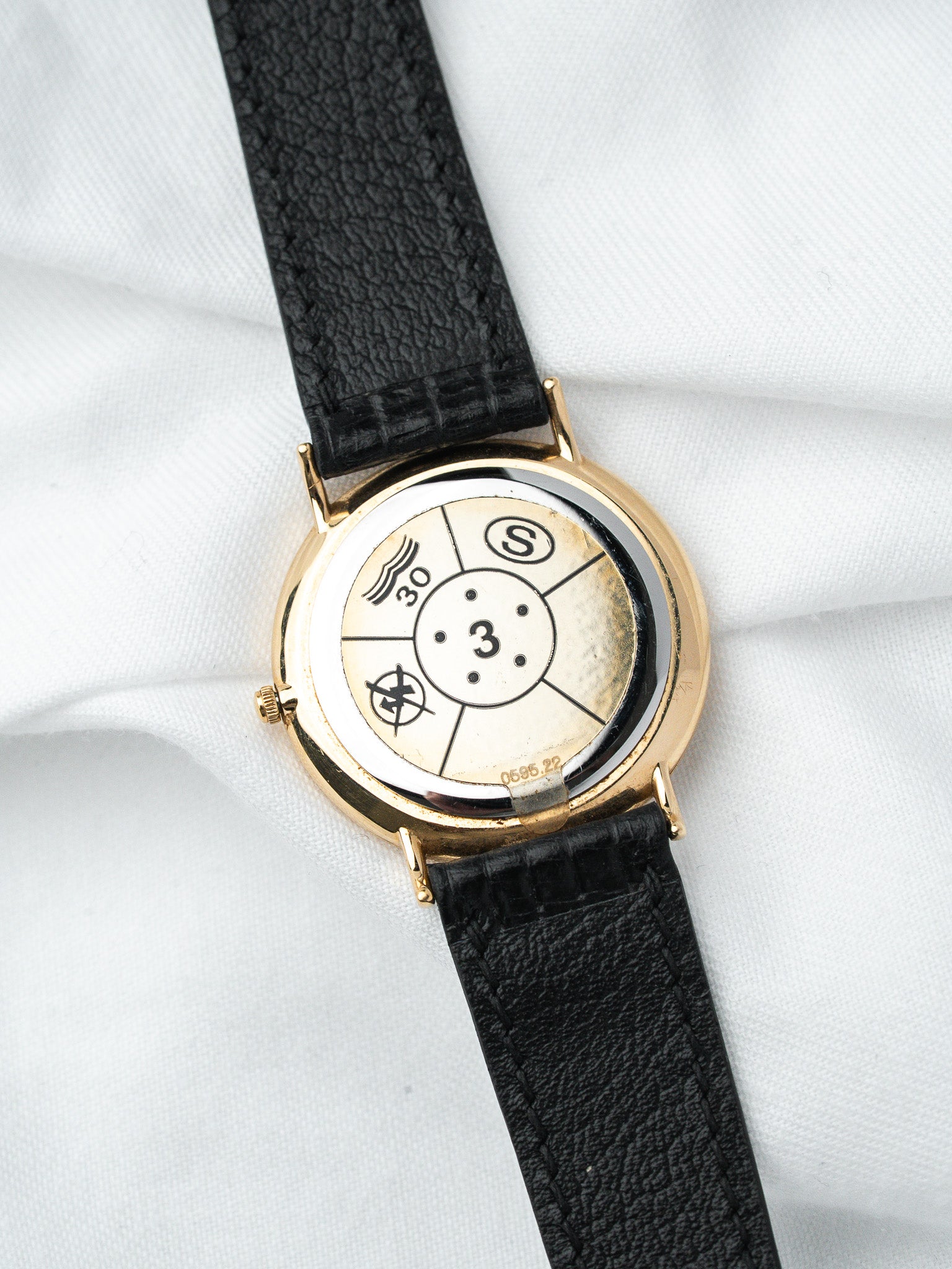Vintage Universal Genève watch with gold case, black leather strap, and unique dial design