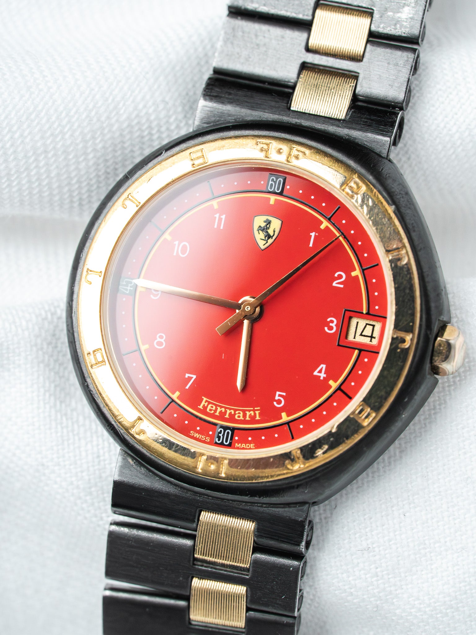 Ferrari vintage watch with red dial, gold accents, black bracelet on white background
