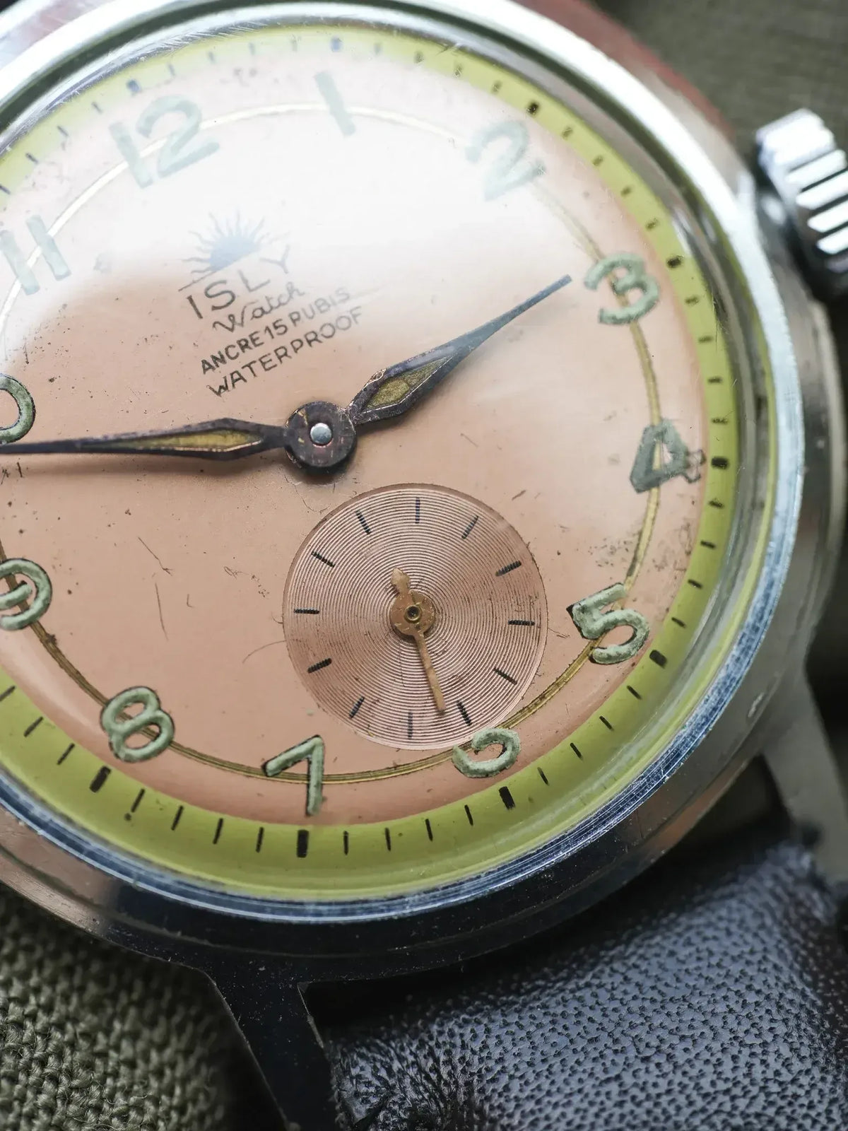 ISLY vintage watch with pink dial, green numerals, and textured subdial on fabric