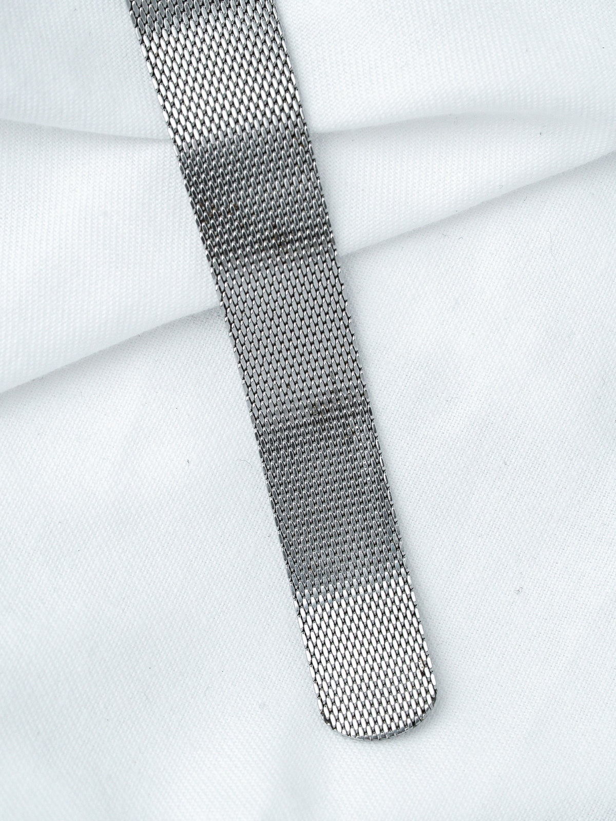 Vintage metal mesh watch strap on white fabric background