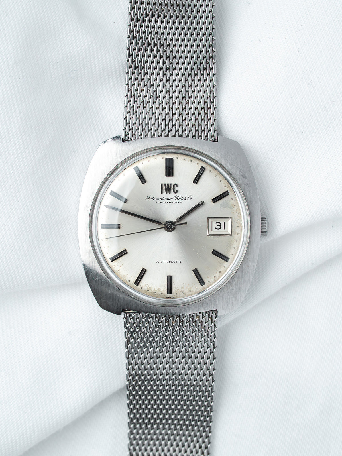 IWC vintage automatic watch with silver dial, black markers, and mesh bracelet