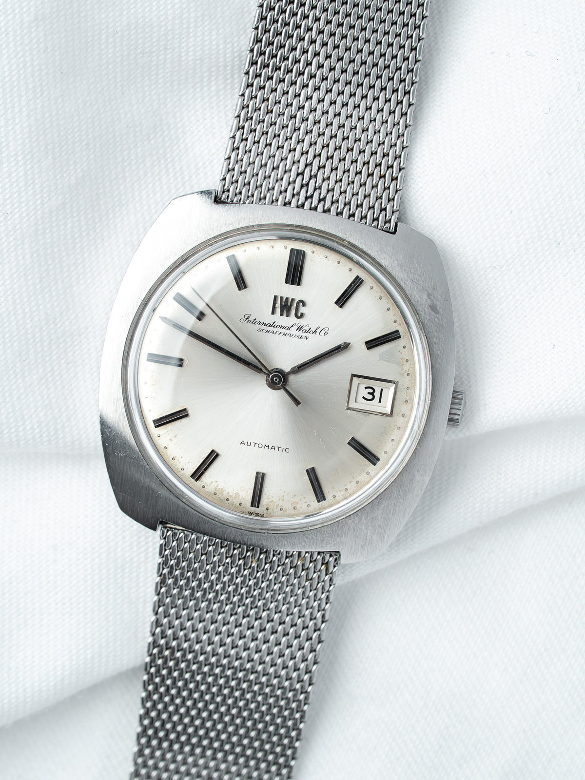 IWC vintage automatic watch with silver dial, black markers, and mesh bracelet on white background