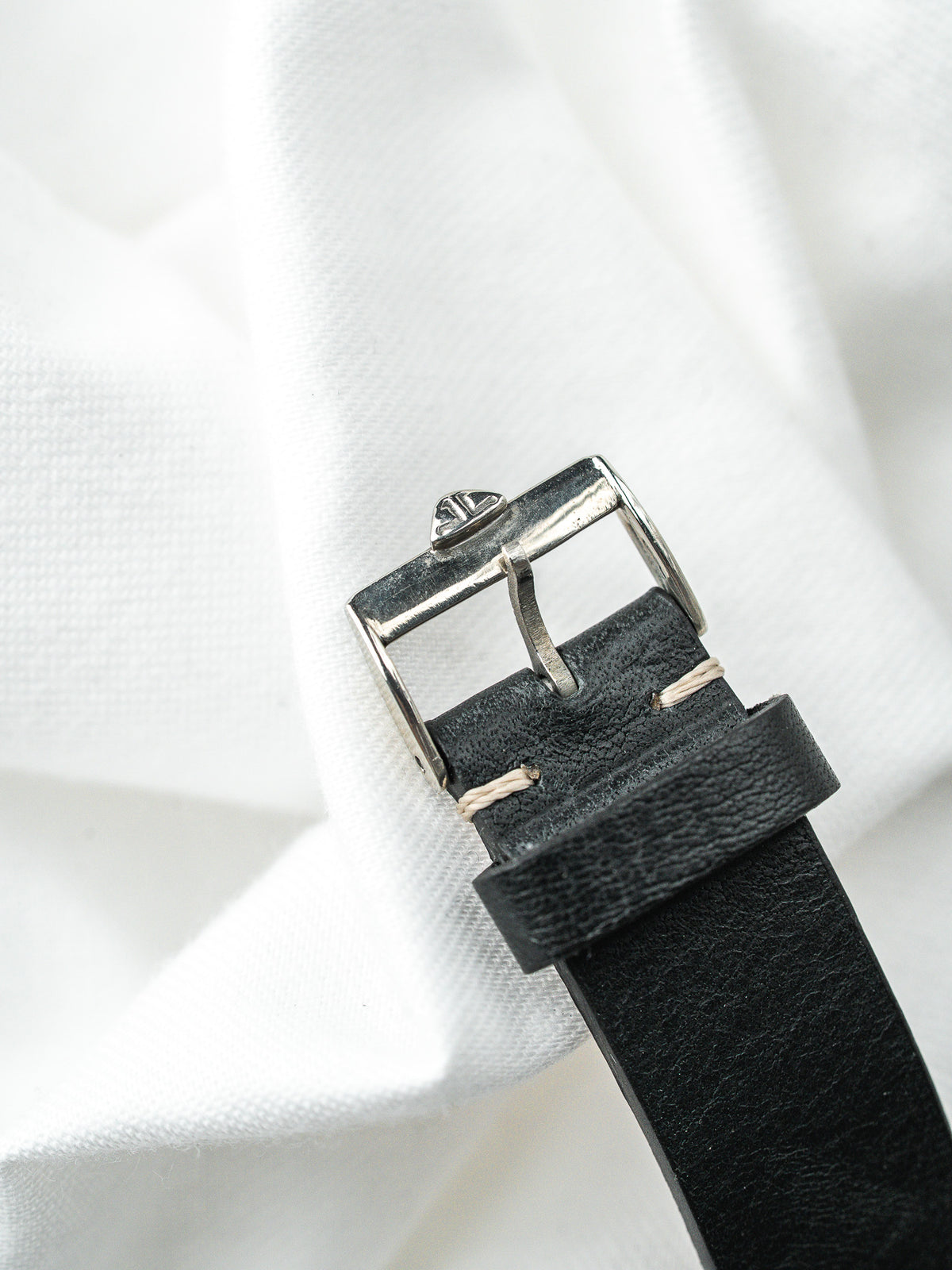 Edelstahlschließe eines schwarzen Lederarmbands für eine Watch auf weißem Hintergrund