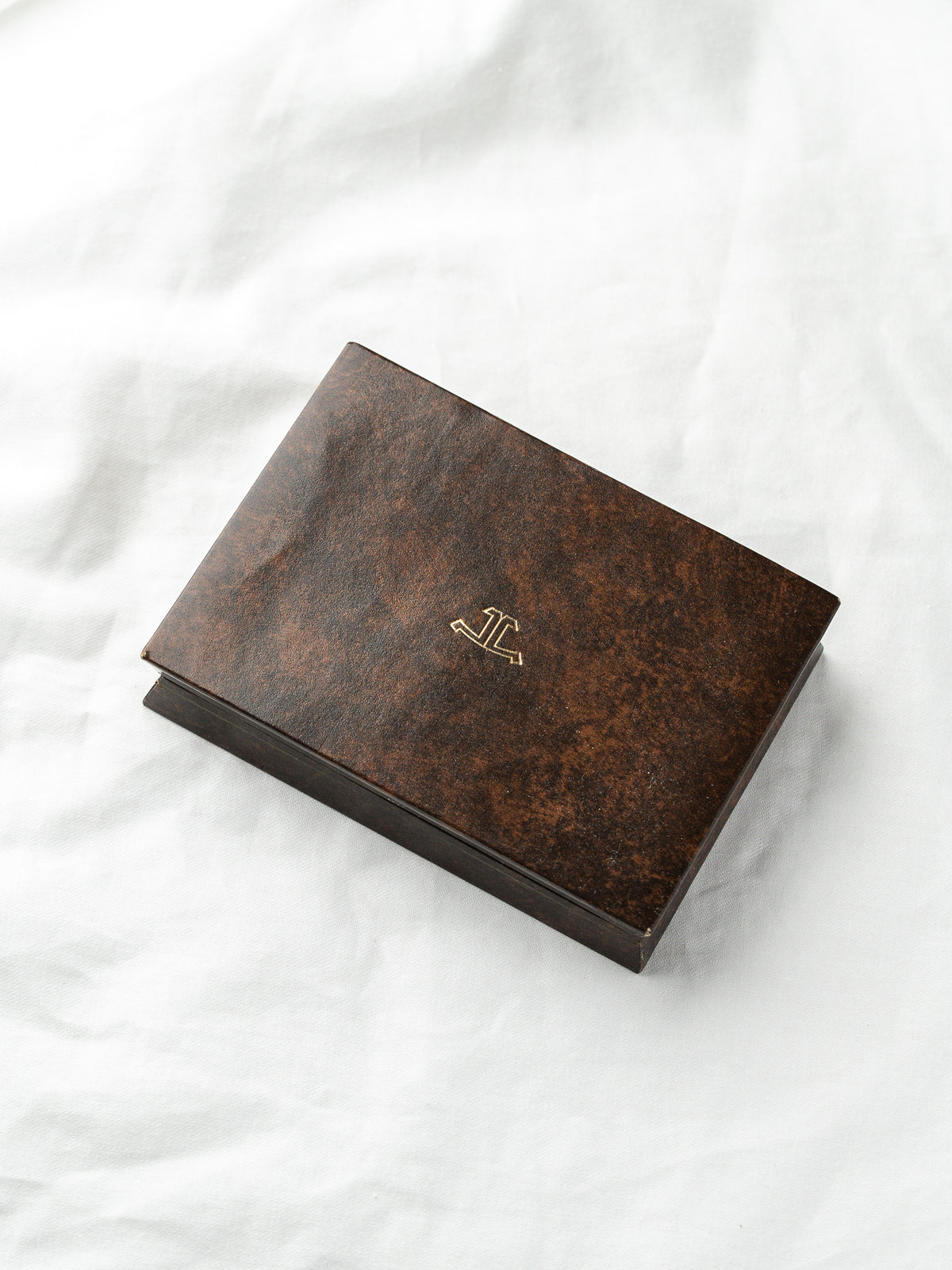 Vintage Etui aus braunem Leder mit goldenem Logo, auf einem weißen Hintergrund platziert