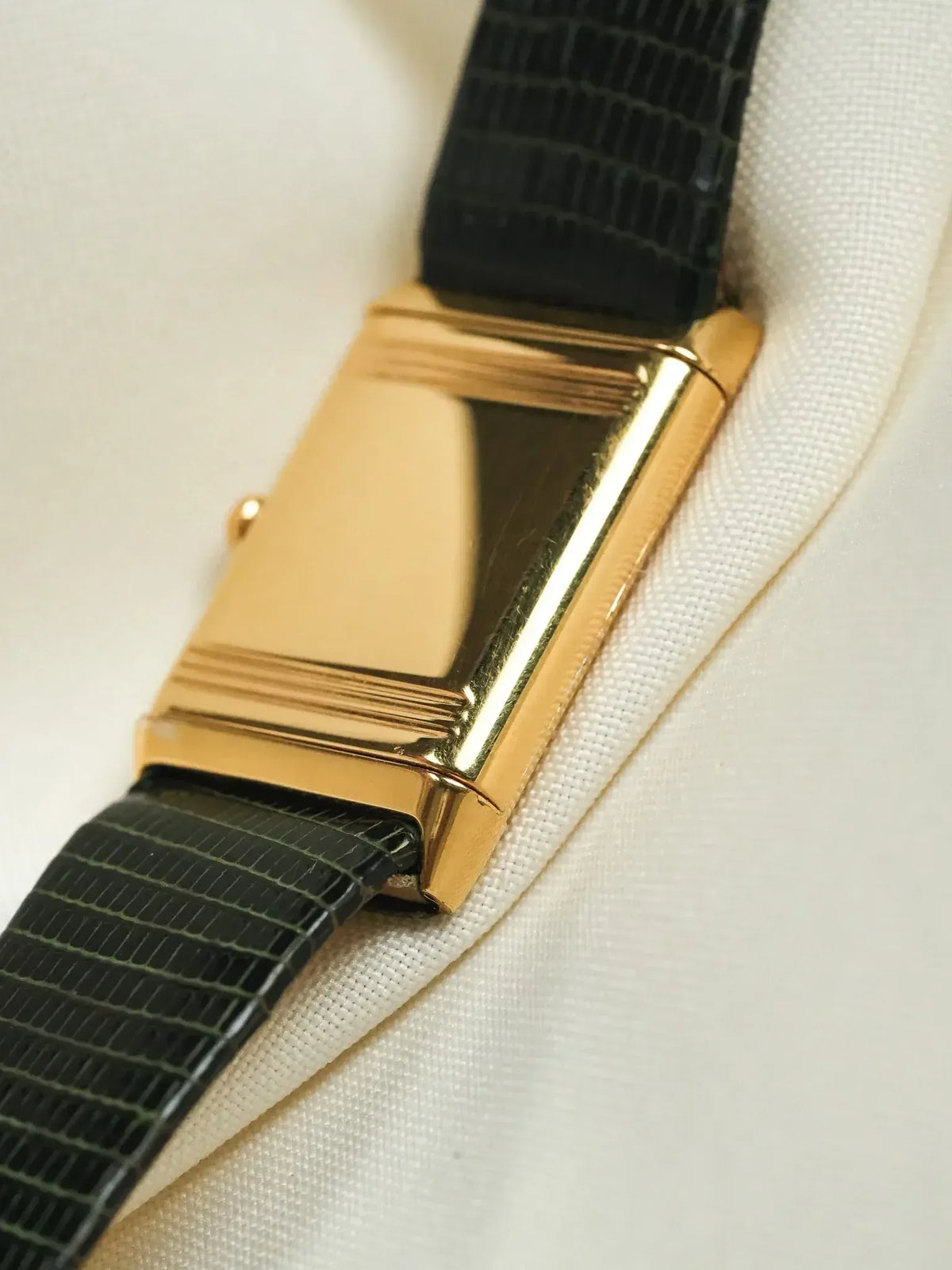 Vintage Cartier Tank watch with gold case and black alligator strap on white fabric