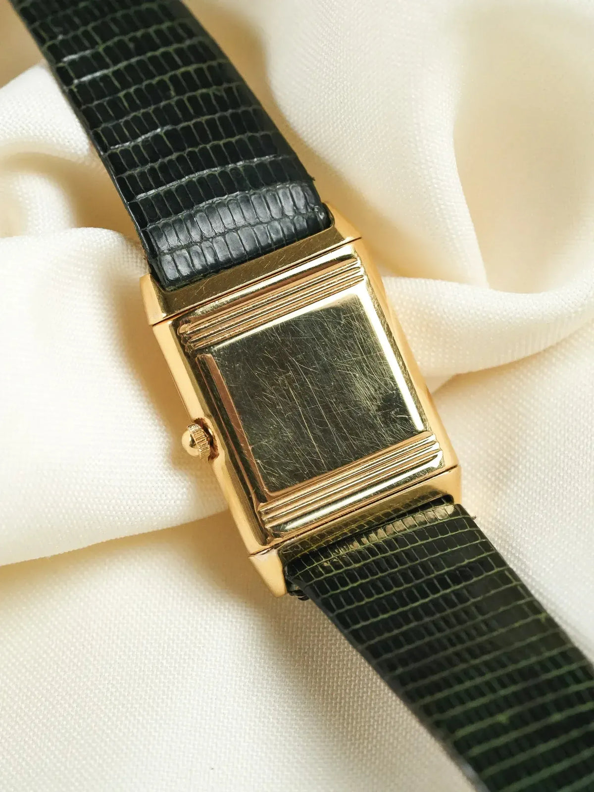 Vintage rectangular gold watch with black alligator strap on cream fabric