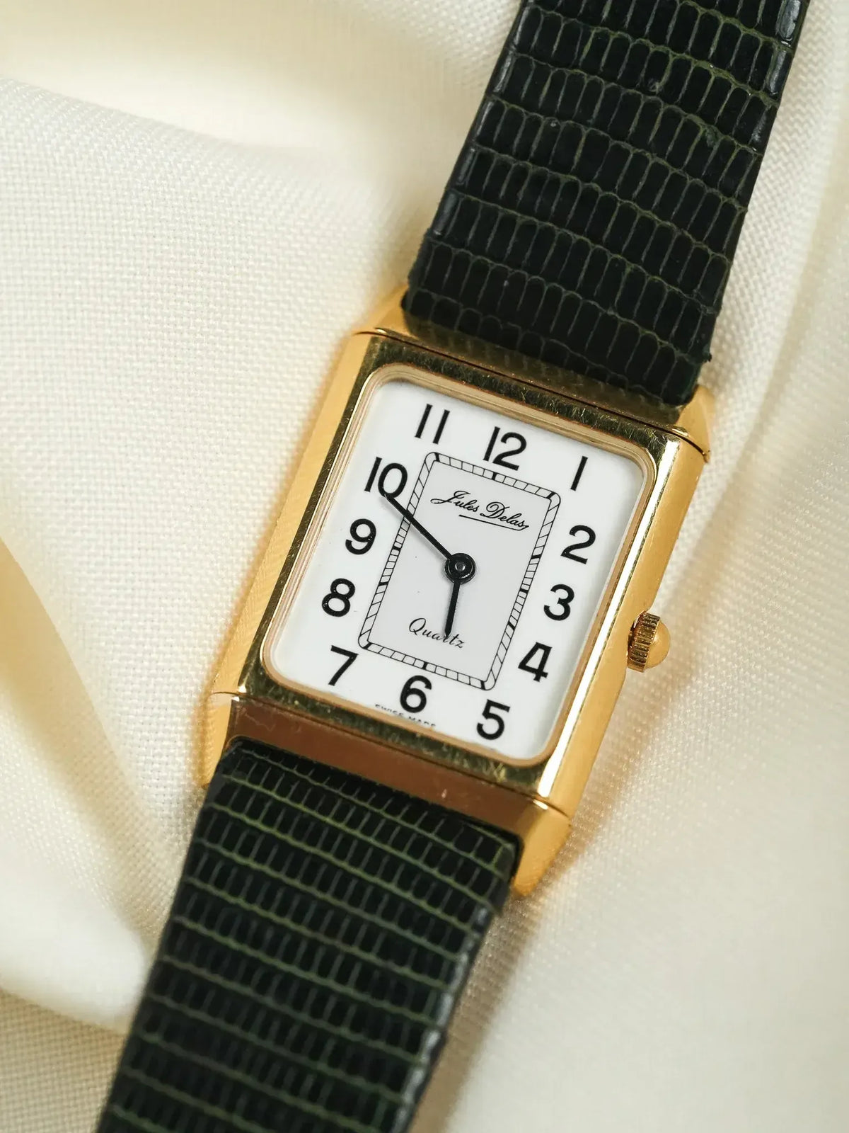 Jules Delas vintage quartz watch with gold case, white dial, black strap on fabric