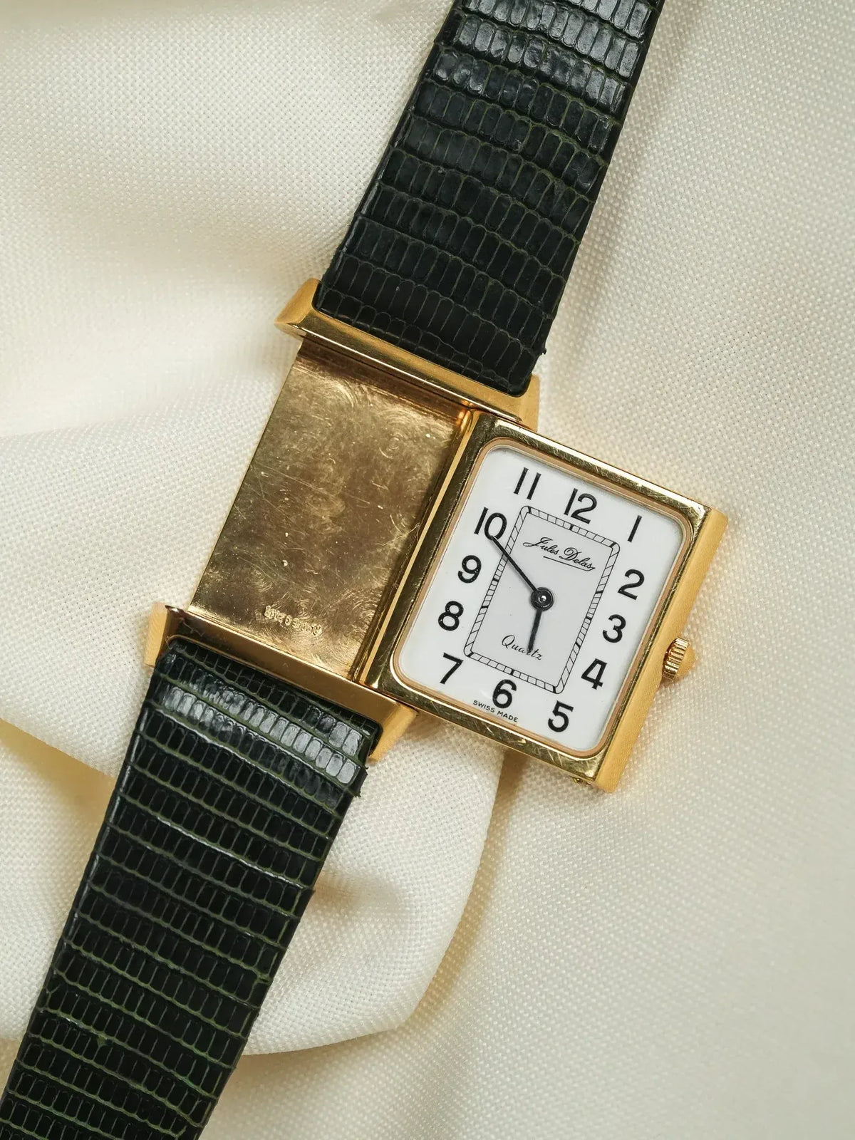 Jules Jules vintage watch with gold case, white dial, black lizard strap on cream fabric