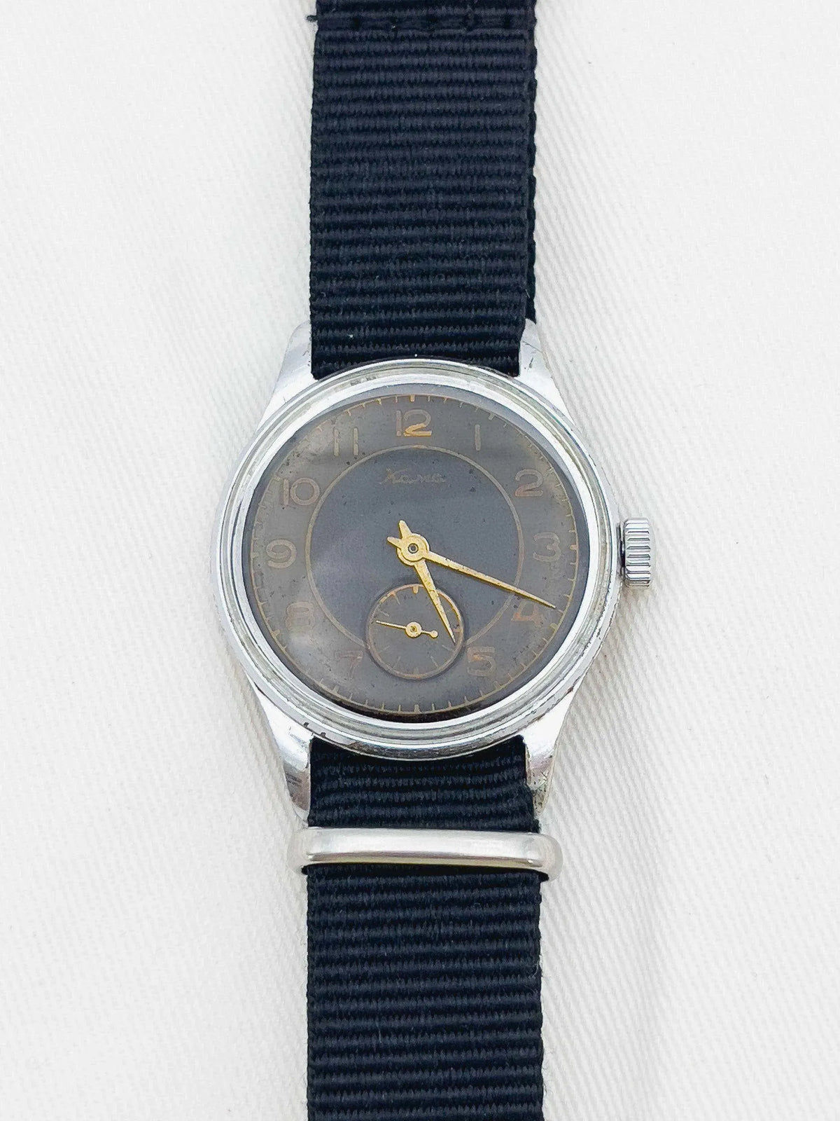 Vintage Xema watch with grey dial, gold hands, steel case, and black fabric strap