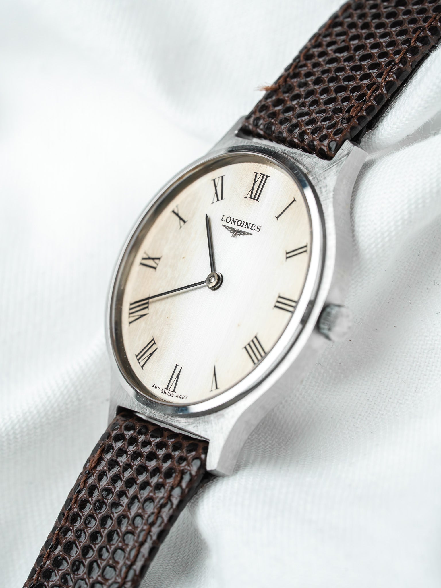 Longines vintage watch with silver case, cream dial, Roman numerals, brown textured strap