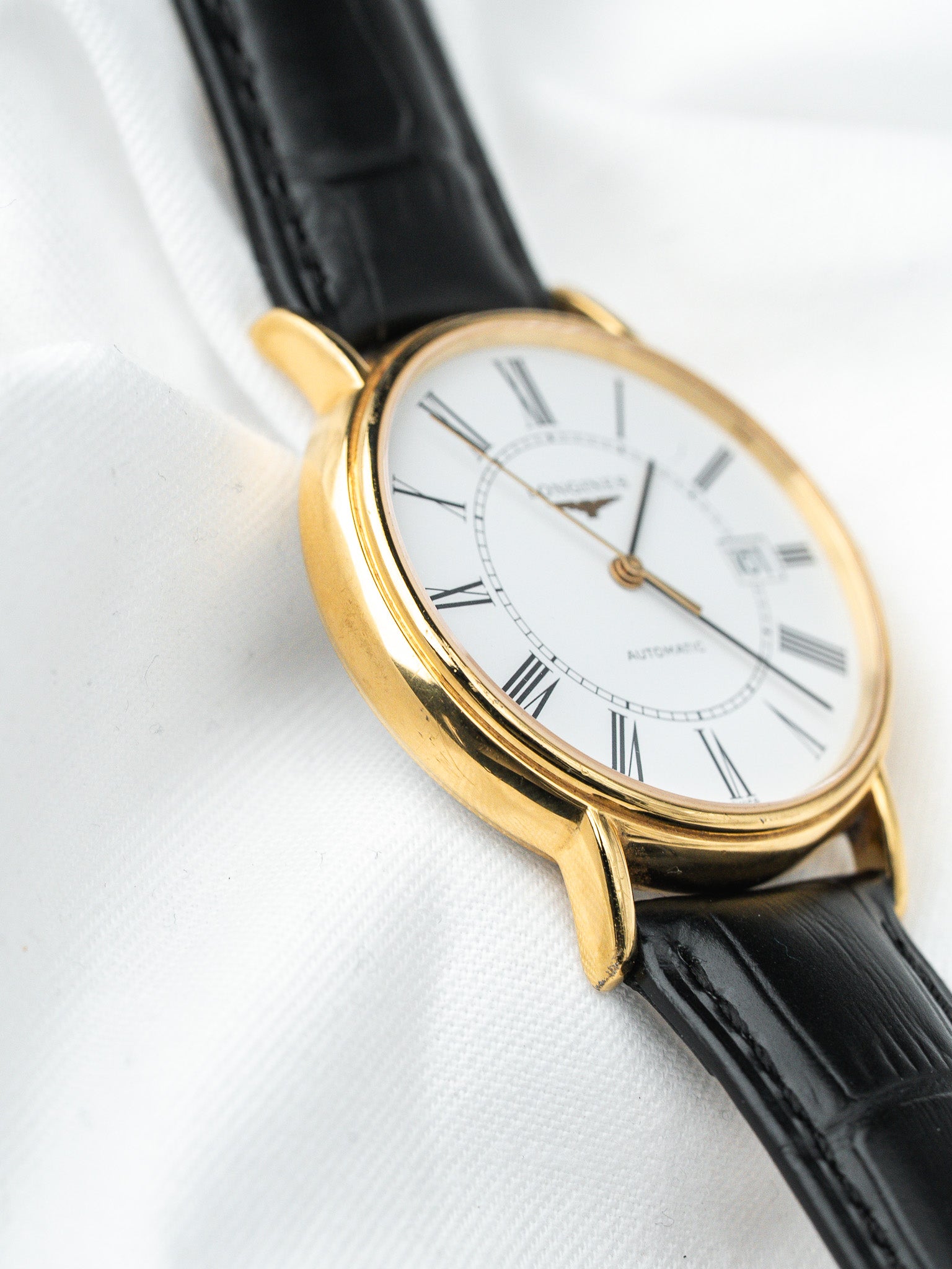 Longines vintage watch with gold case, white dial, Roman numerals, black leather strap