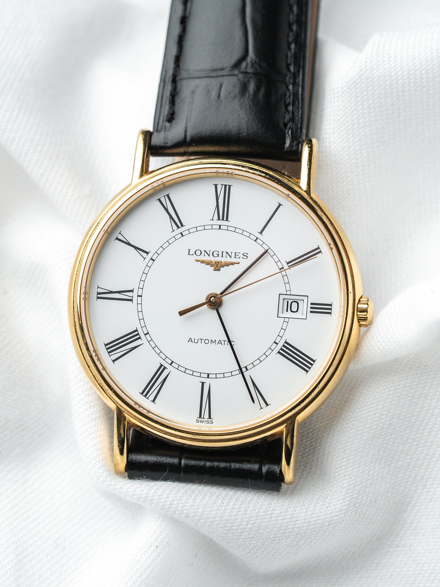 Longines vintage automatic watch with gold case, white dial, Roman numerals, black leather strap