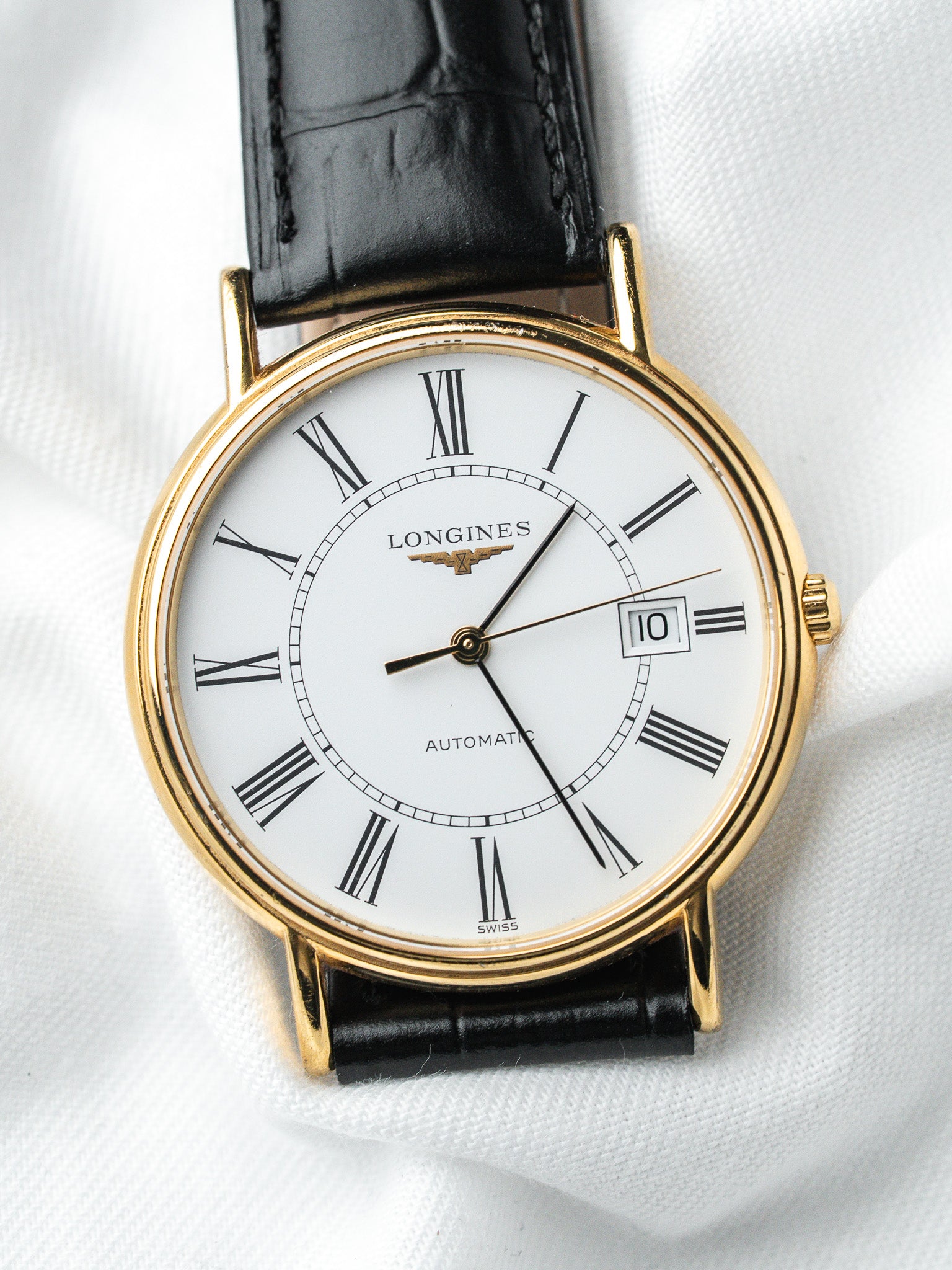 Longines vintage automatic watch with gold case, white dial, Roman numerals, black leather strap