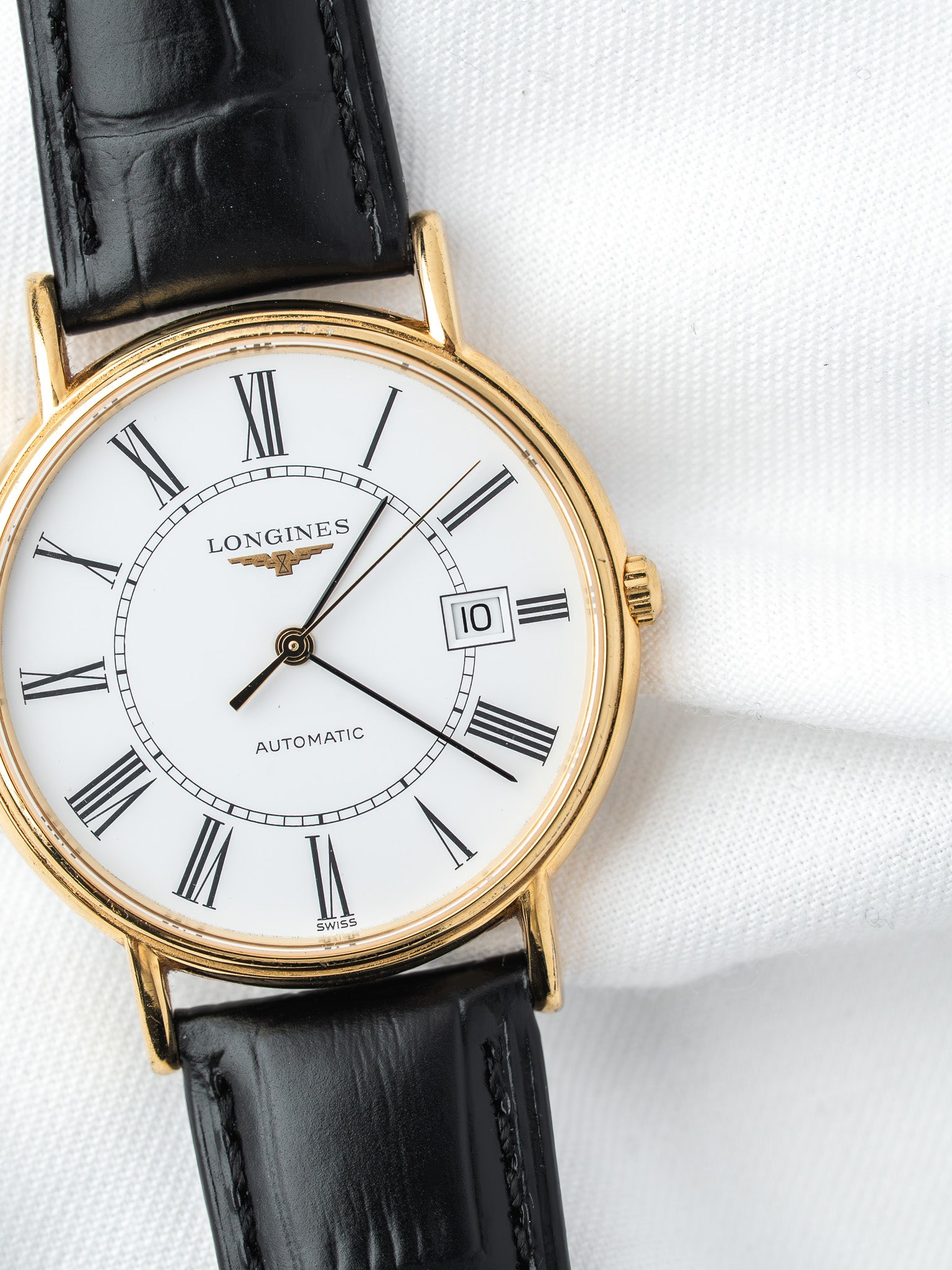 Longines vintage automatic watch with gold case, white dial, Roman numerals, black leather strap