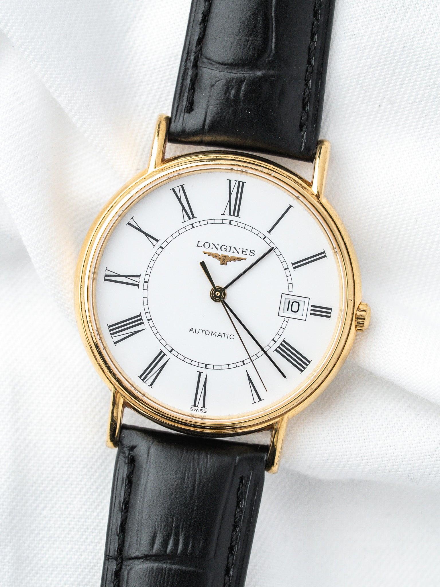 Longines vintage automatic watch with gold case, white dial, Roman numerals, black leather strap