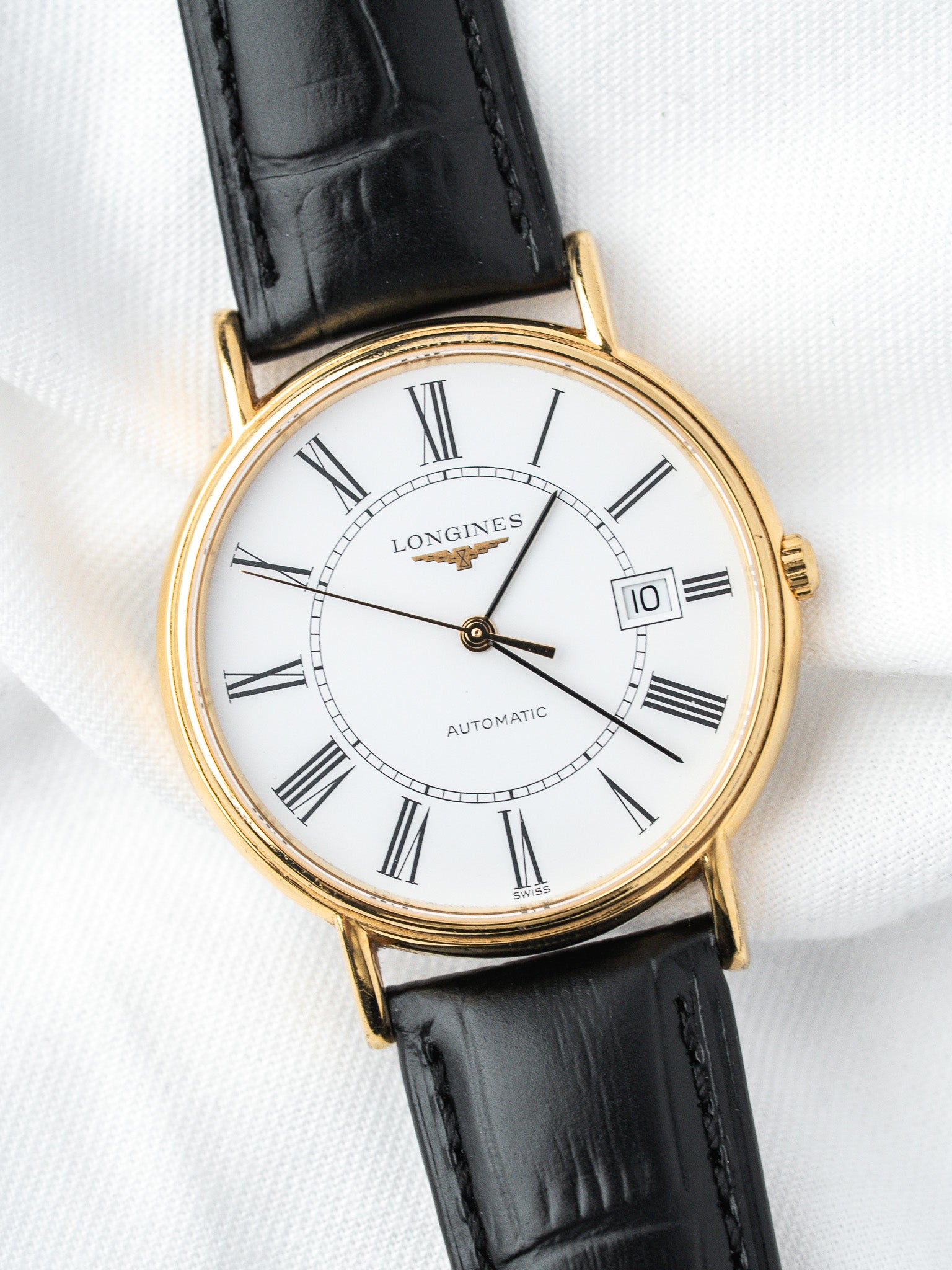 Longines vintage automatic watch with gold case, white dial, Roman numerals, black leather strap