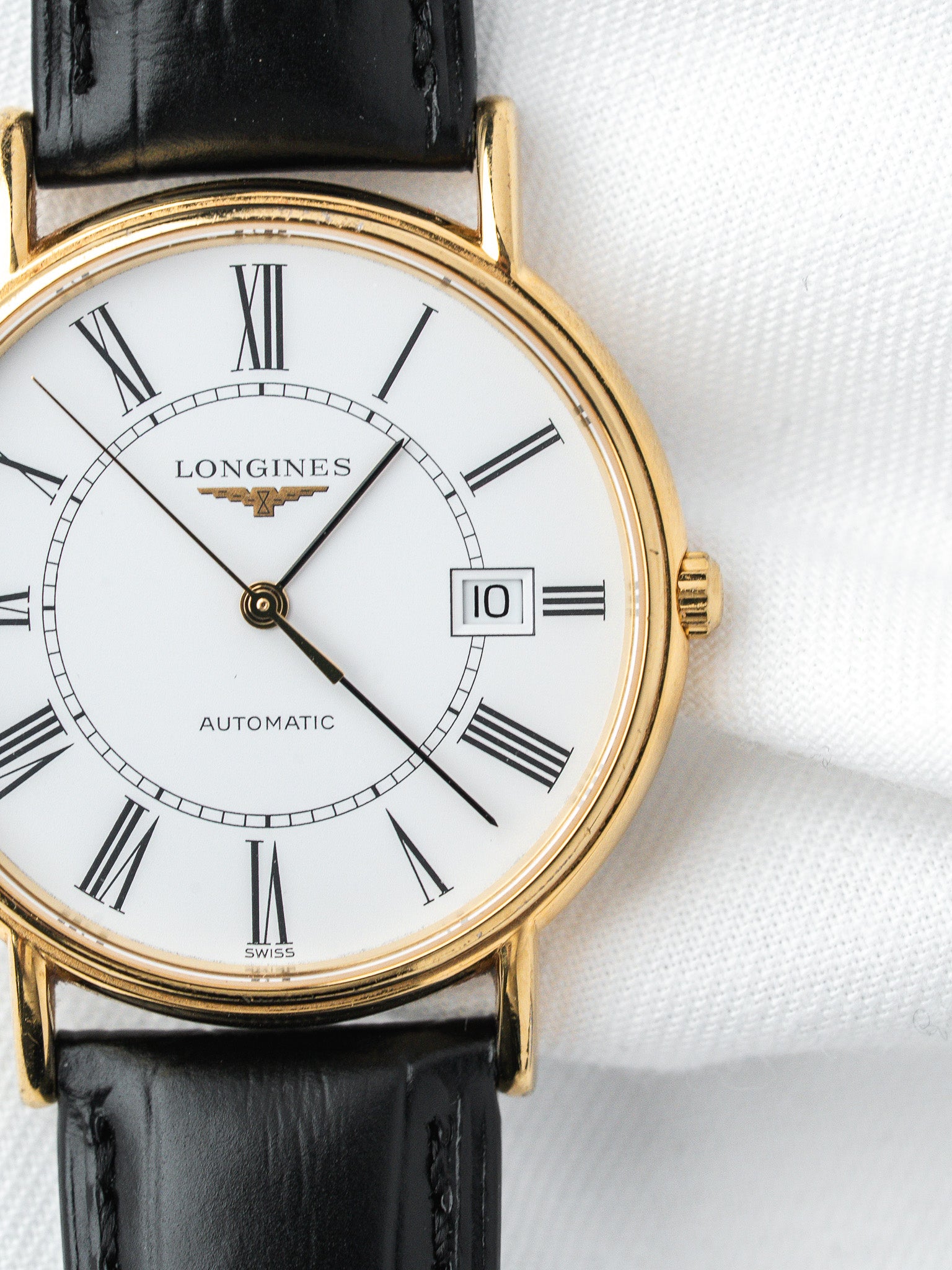 Longines vintage automatic watch with gold case, white dial, Roman numerals, black leather strap