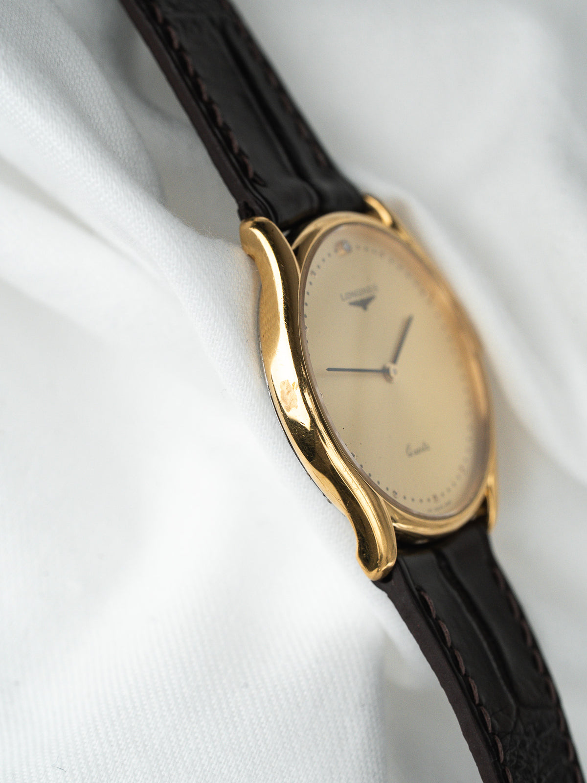 Montre Longines vintage en or, cadran champagne et bracelet en cuir noir