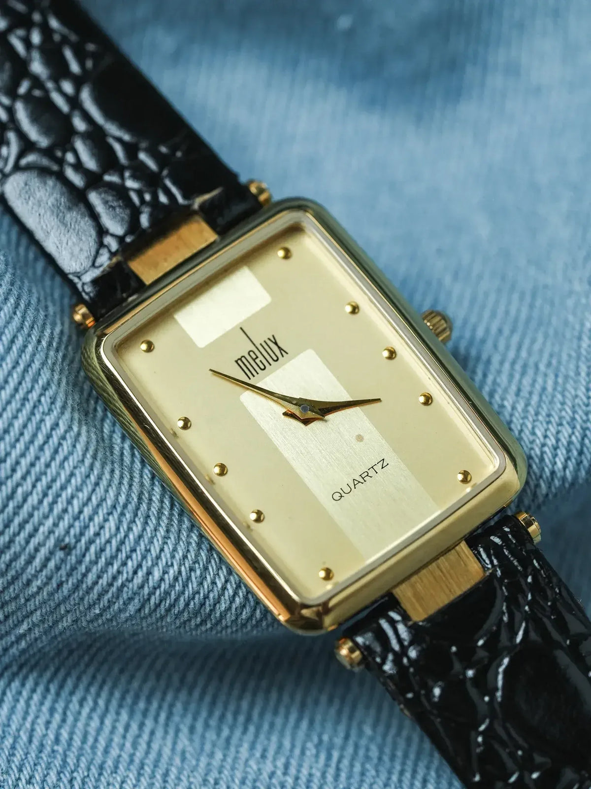 Melux vintage quartz watch with gold case, cream dial, black croco strap on denim