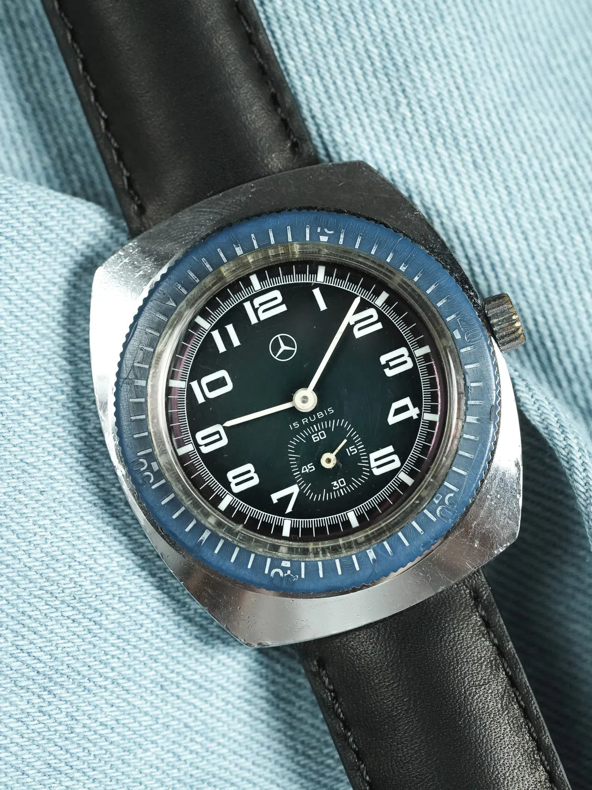 Vintage Mercedes-Benz watch with black dial, blue bezel, and black leather strap