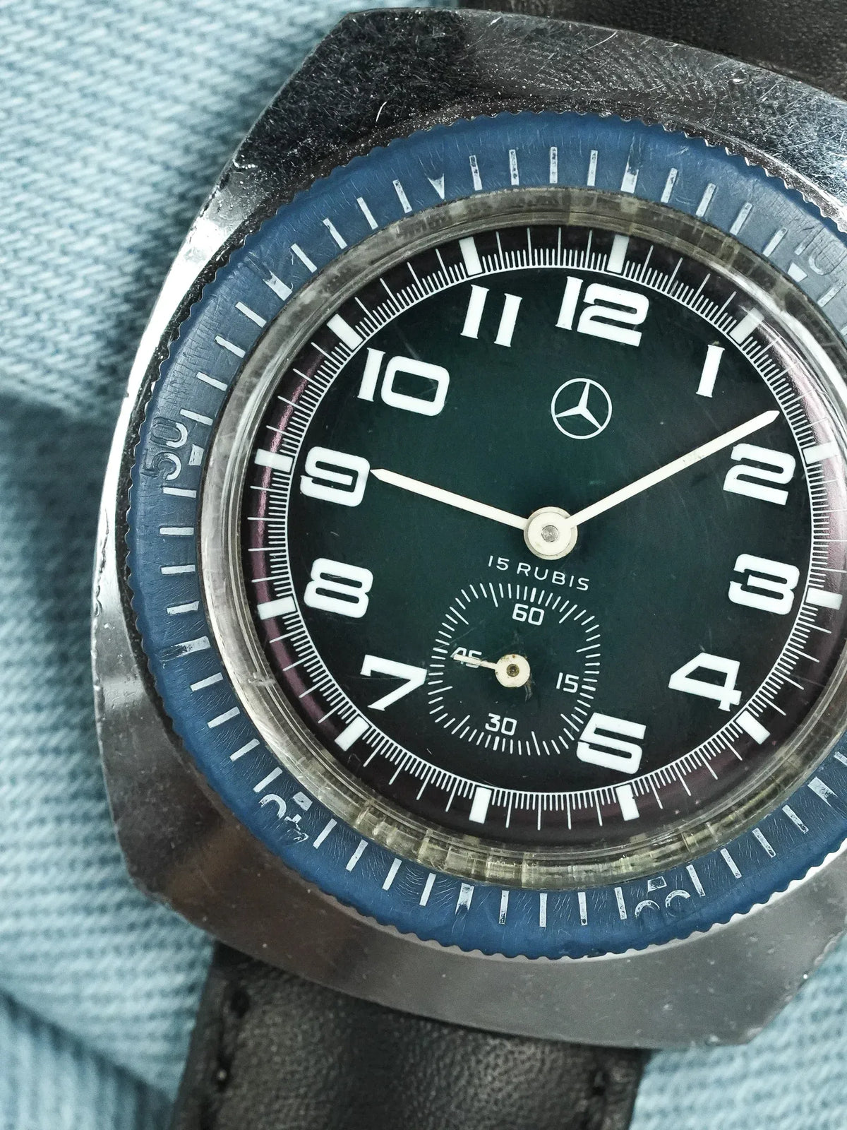 Vintage Mercedes-Benz watch with black dial, blue bezel, and leather strap