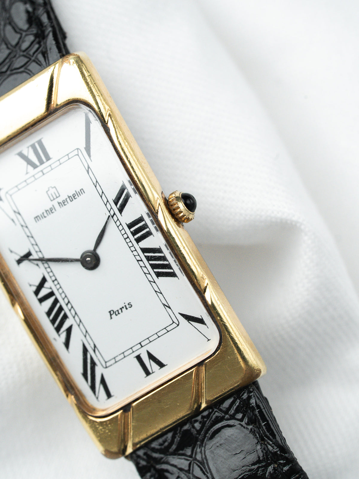 Montre Michel Herbelin vintage, boîtier rectangulaire doré, cadran blanc et bracelet cuir noir