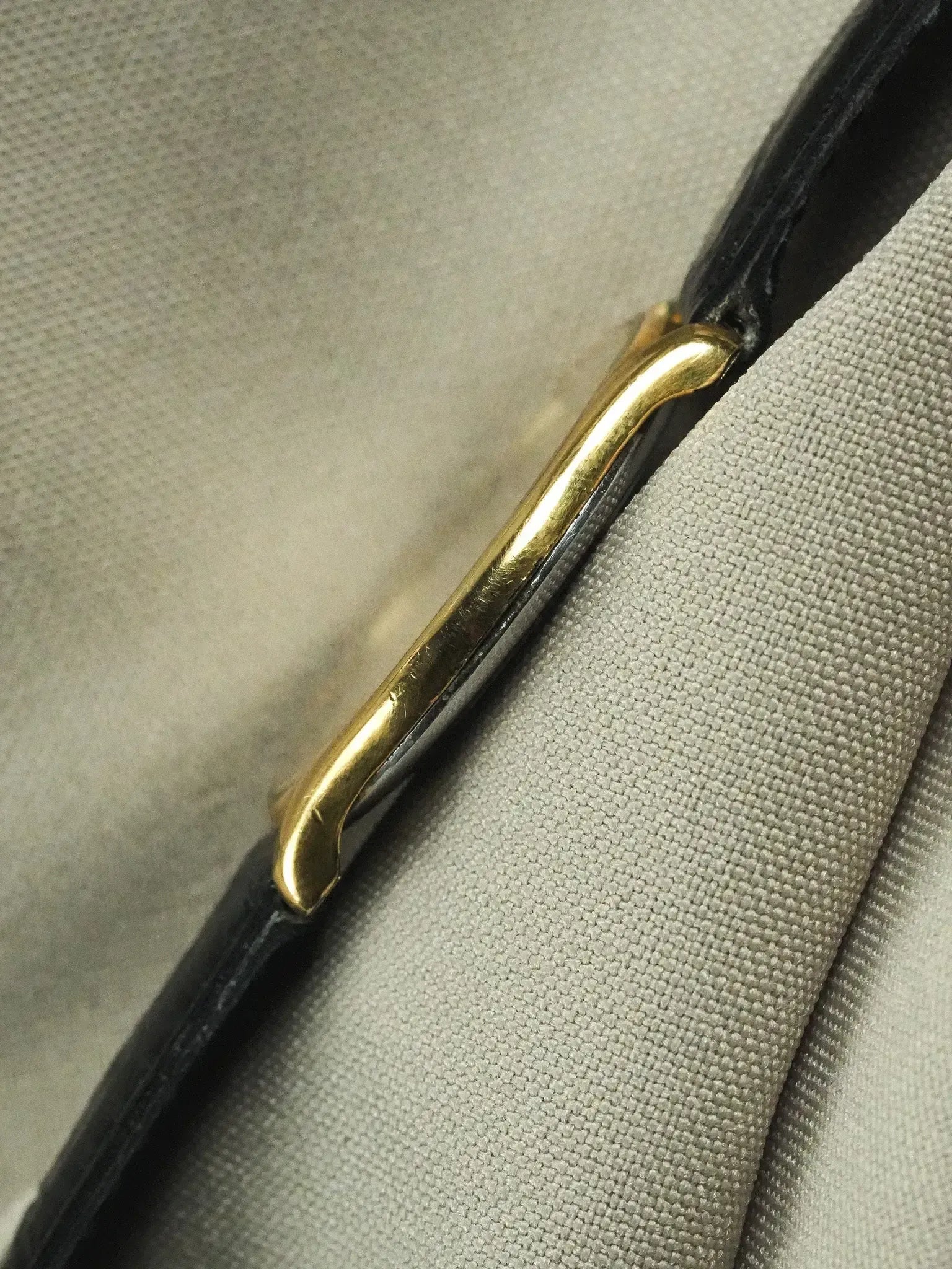 Vintage Cartier watch with gold crown and black leather strap on textured fabric