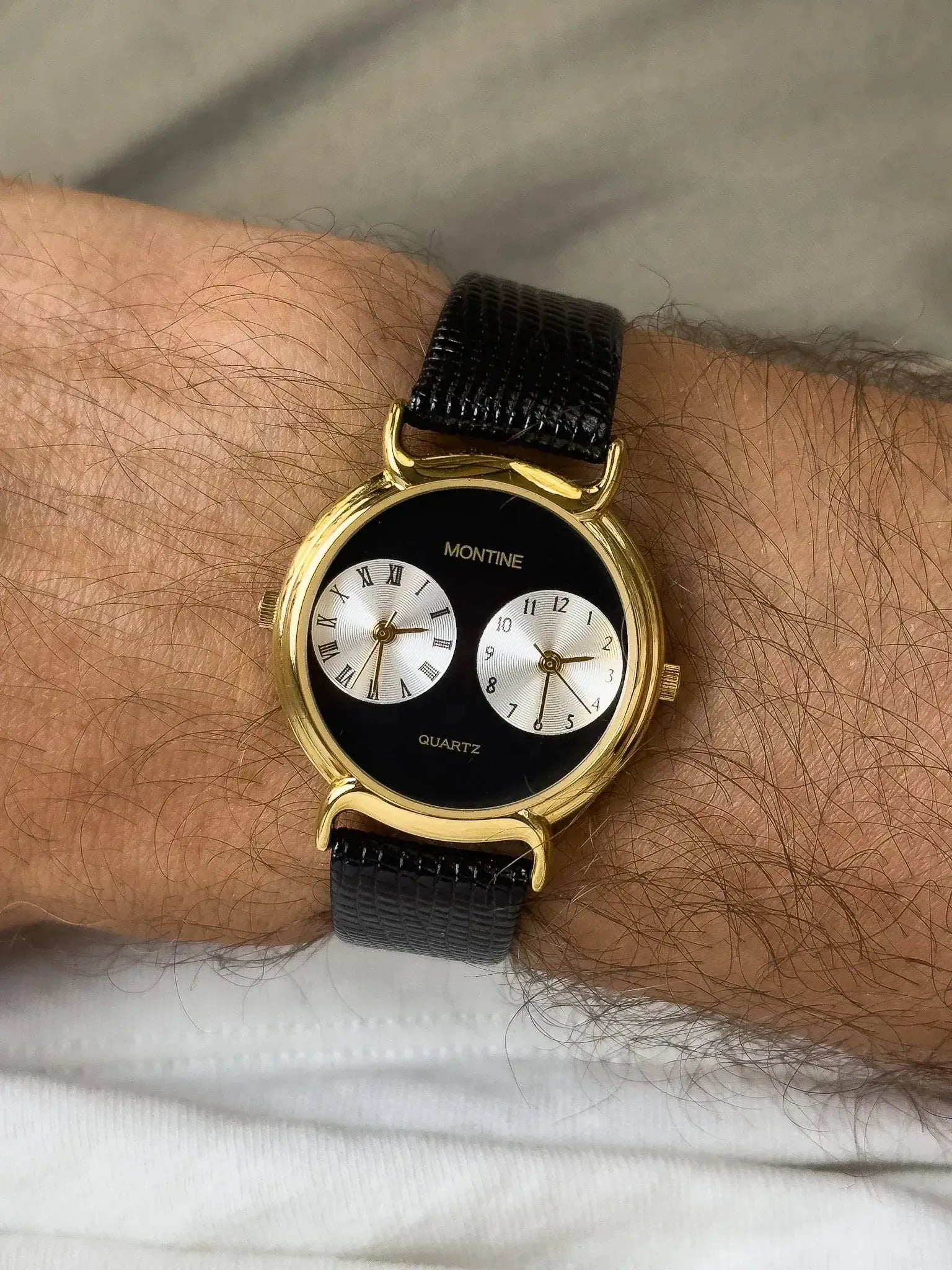 Montine vintage watch with gold case, black dial, dual subdials, and black textured strap worn on wrist