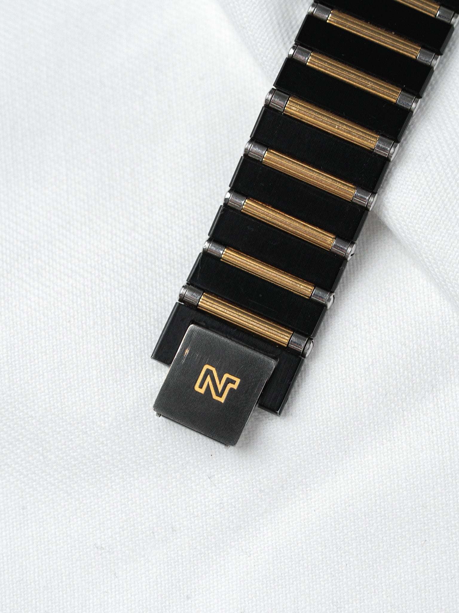 Vintage Omega watch bracelet with black and gold links, clasp featuring Omega logo