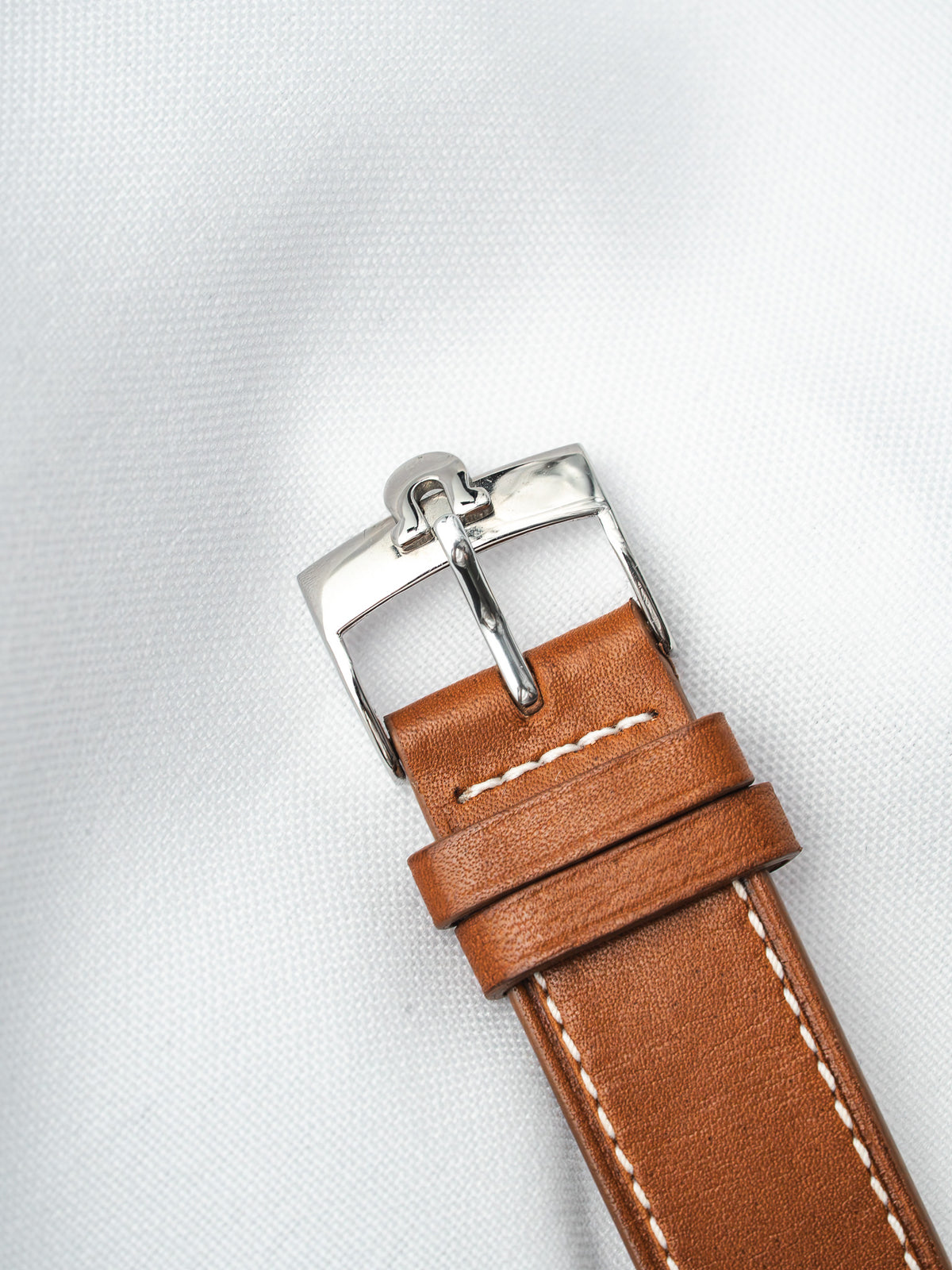 Brown leather watch strap with white stitching and polished steel buckle