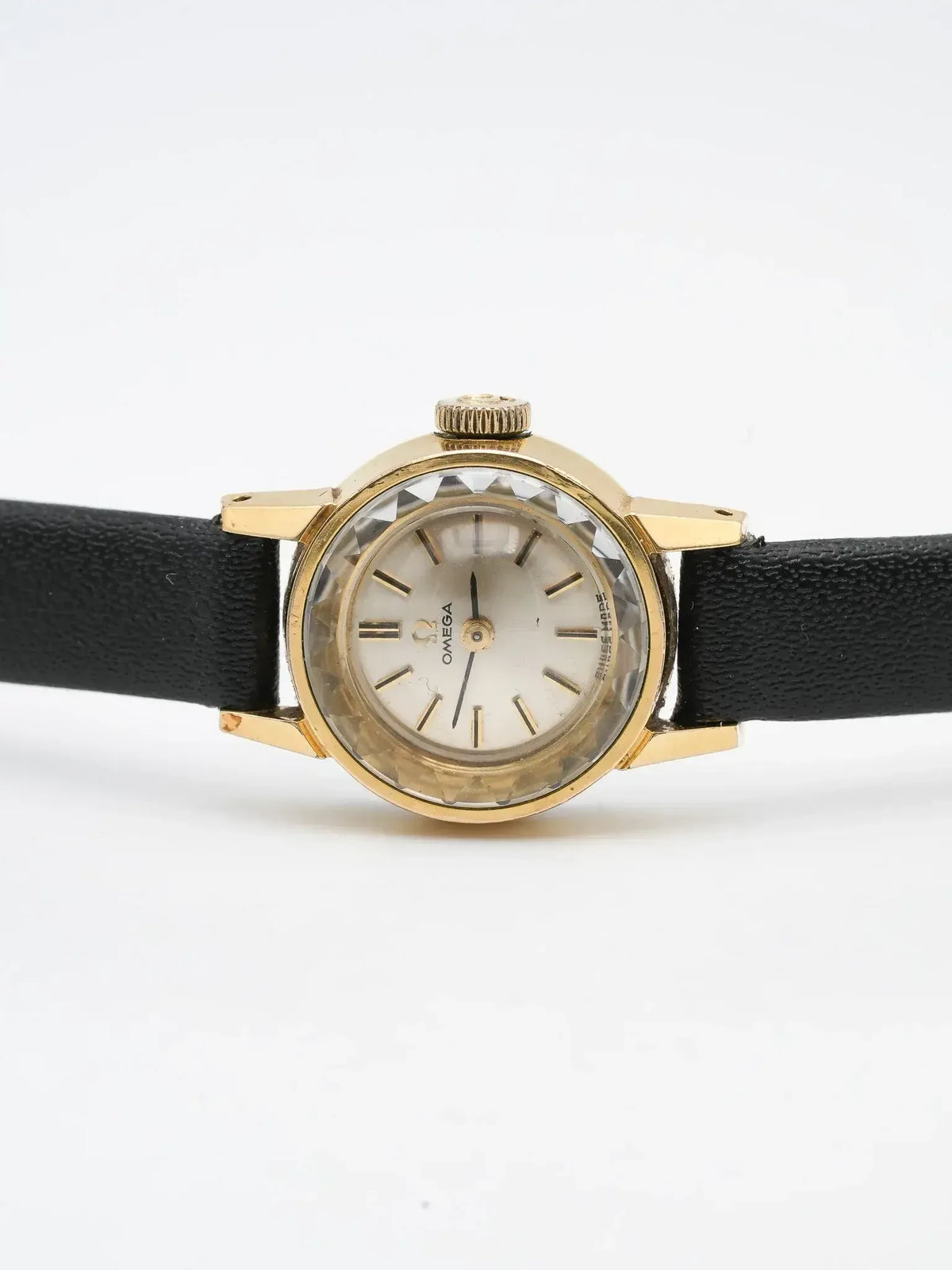 Omega vintage watch with gold case, white dial, black leather strap on white background