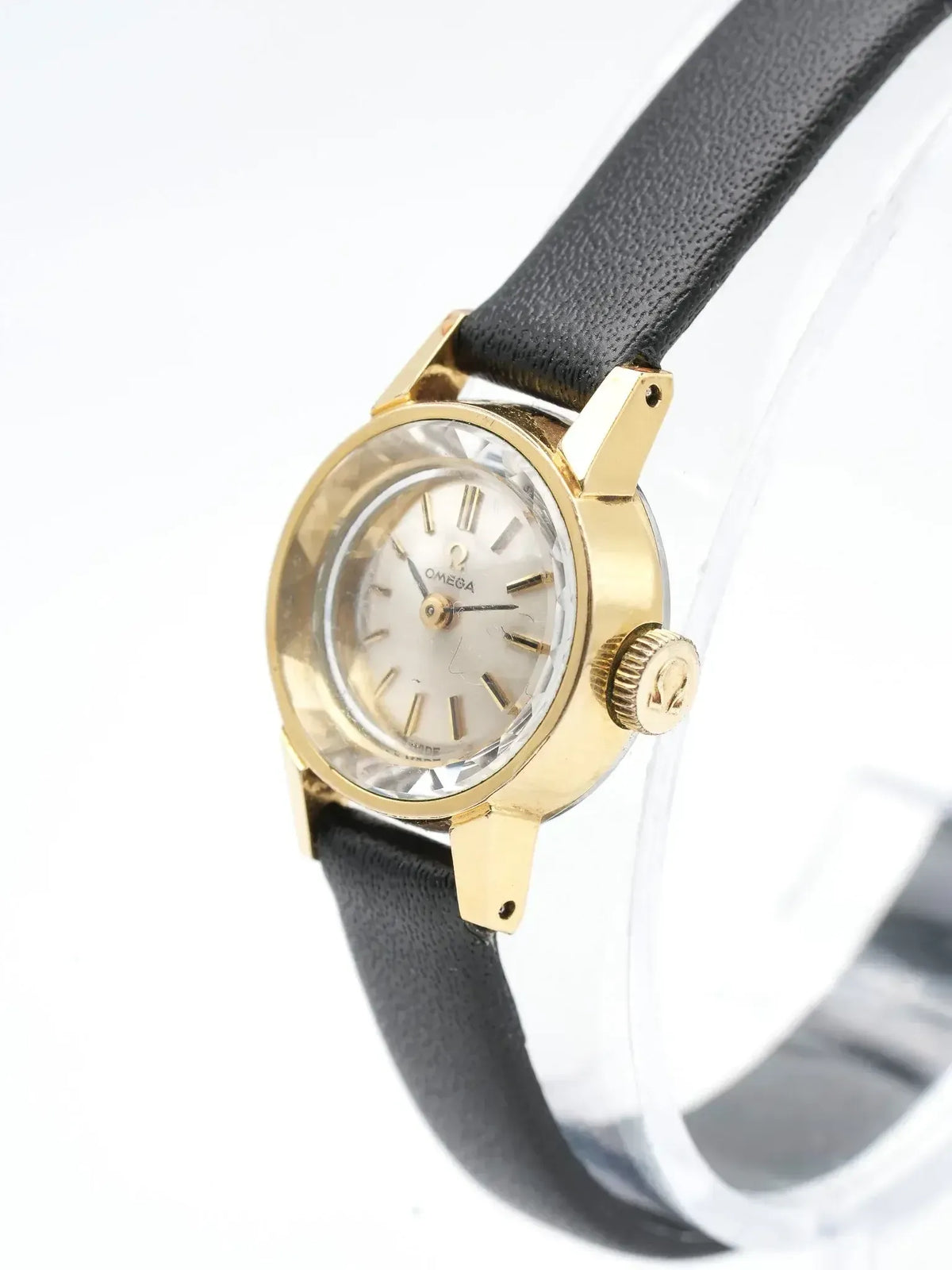 Vintage Omega watch with gold case, silver dial, black leather strap on display