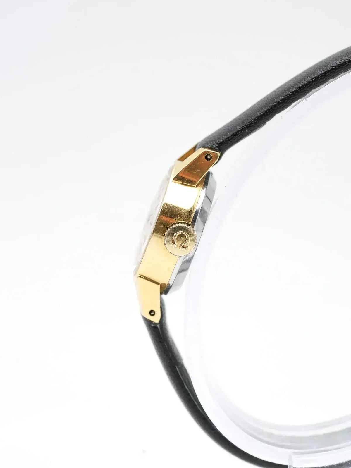 Omega vintage watch with gold case and black leather strap on white background