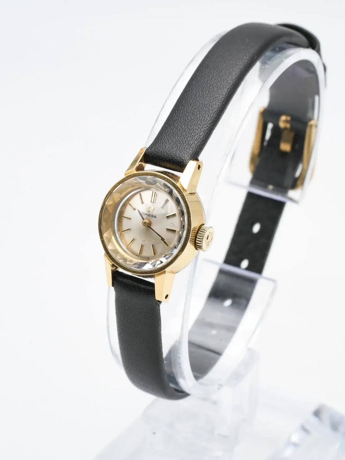 Vintage Omega watch with gold case, silver dial, black leather strap on display stand