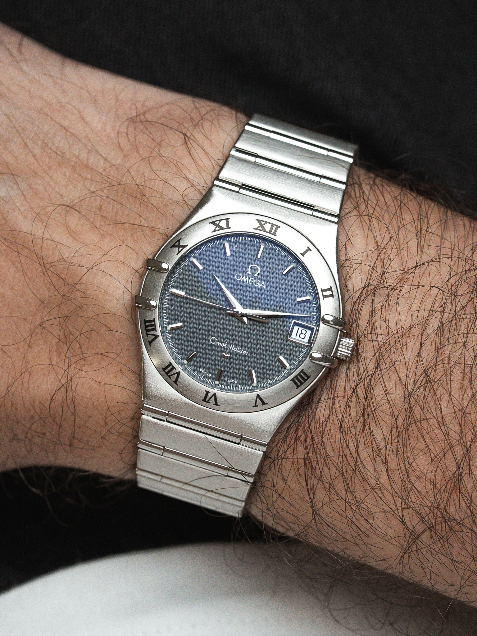 Omega Constellation watch with blue dial and steel bracelet worn on wrist