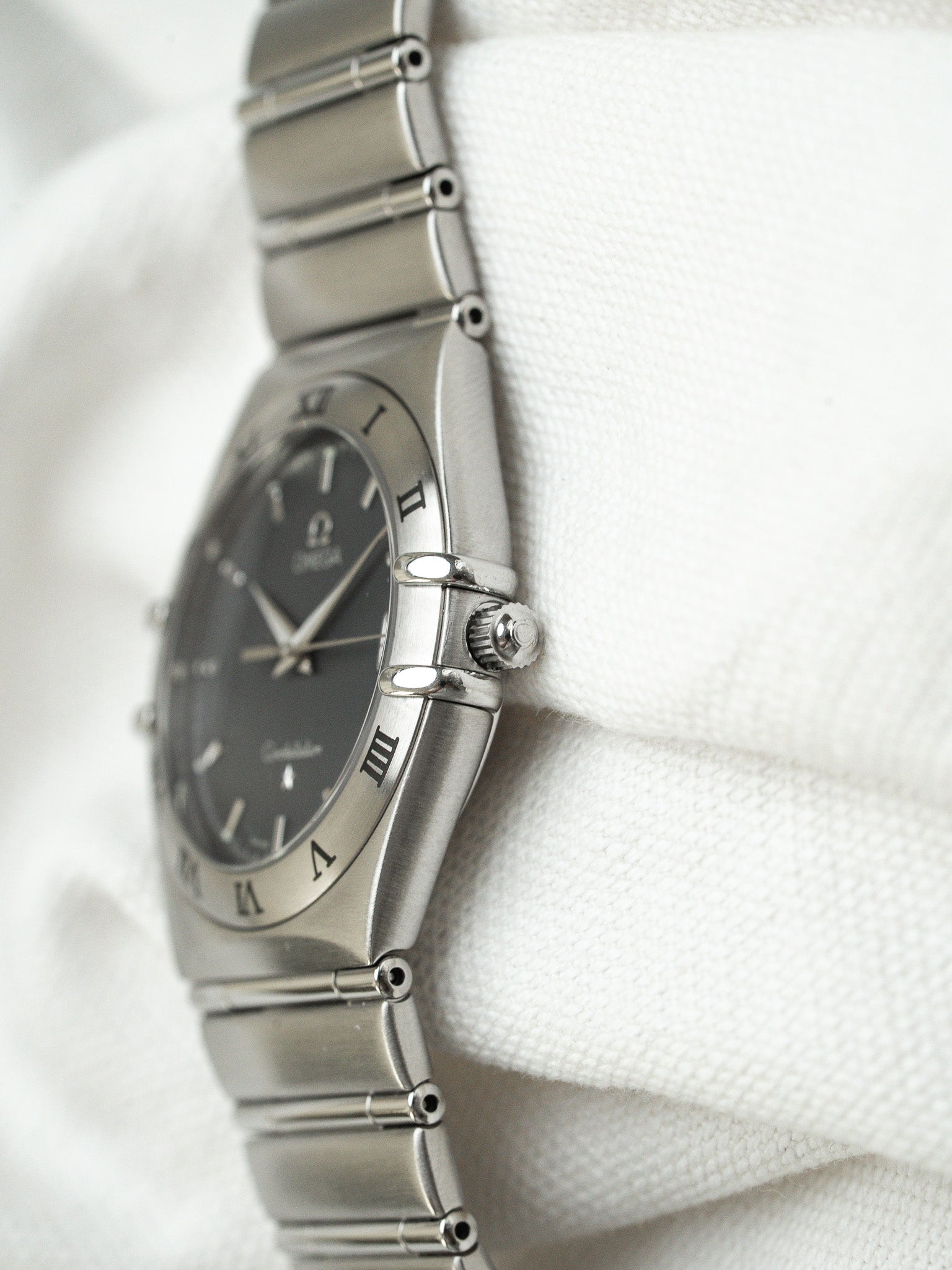 Omega Constellation vintage watch with grey dial, Roman numerals, steel bracelet on white fabric