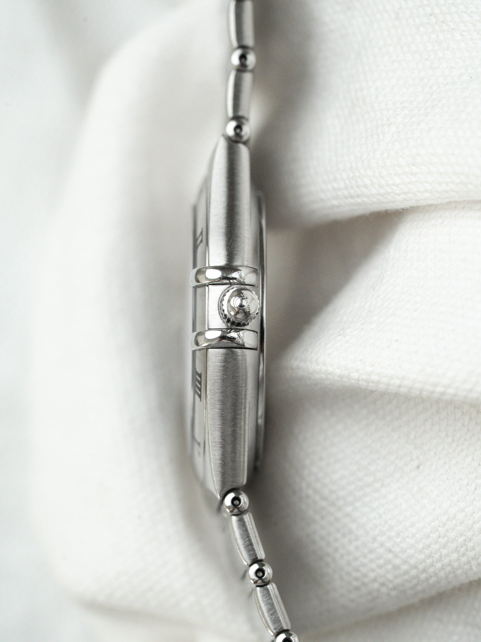 Cartier Tank vintage watch side view, steel case, crown detail on white fabric