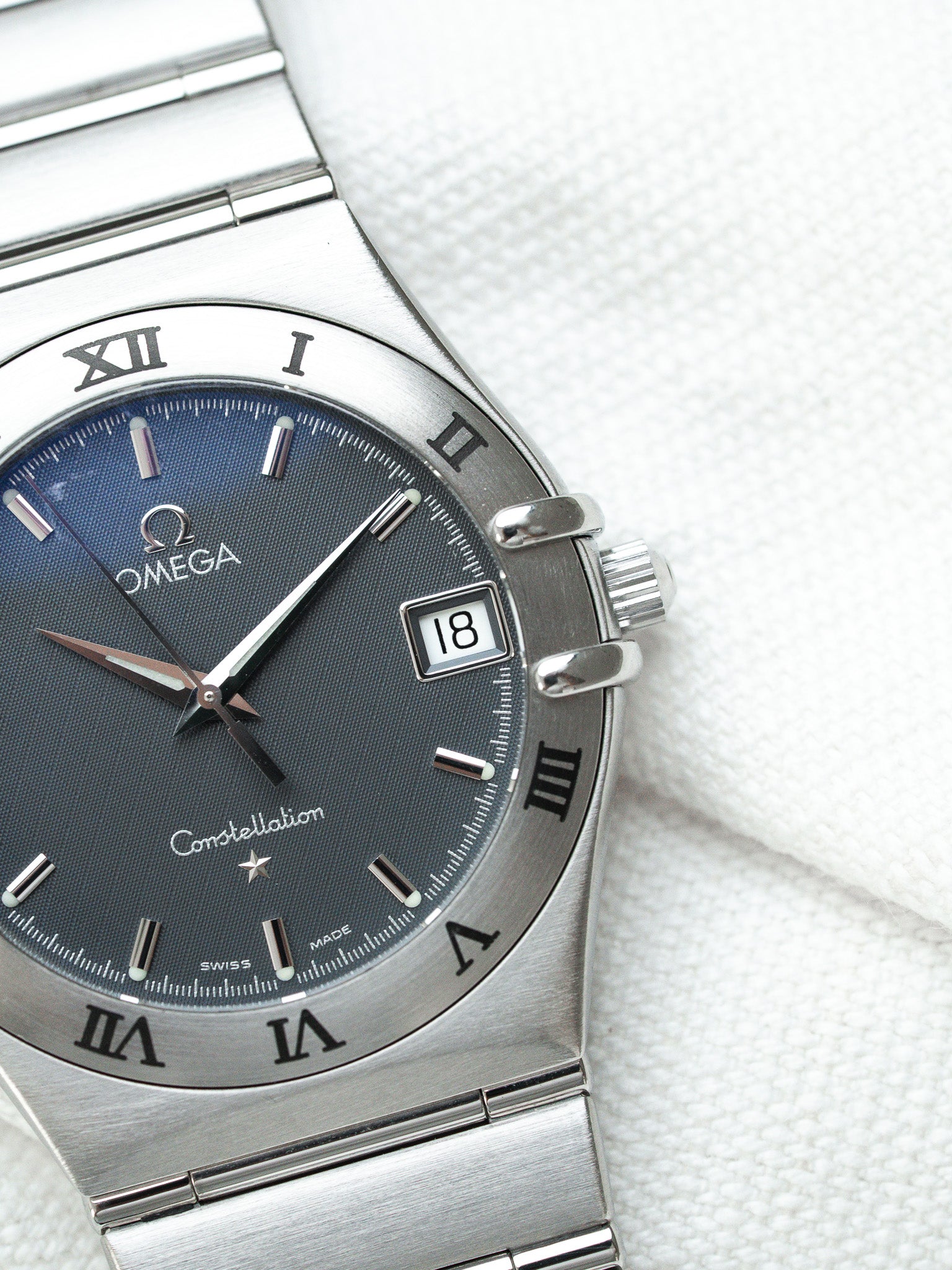 Omega Constellation watch with blue dial, Roman numerals, steel bracelet on white fabric