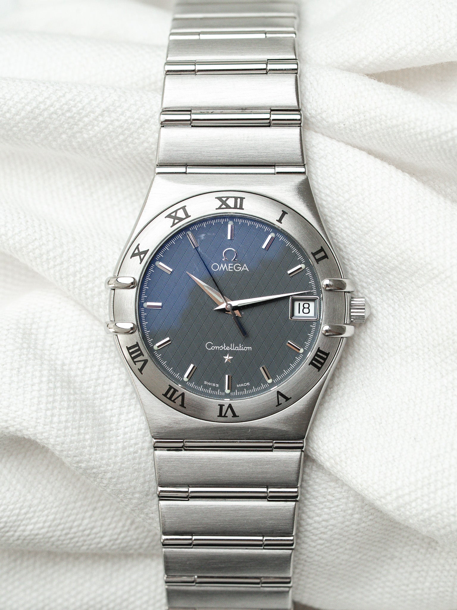 Omega Constellation vintage watch with blue dial, steel bracelet, Roman numerals on white fabric