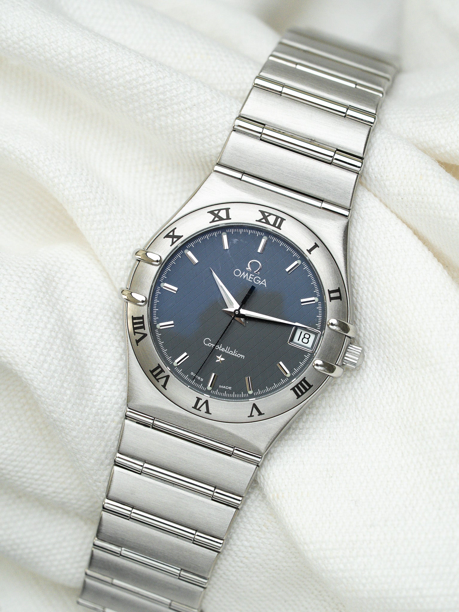 Omega Constellation vintage watch with blue dial, steel bracelet, Roman numerals on white fabric