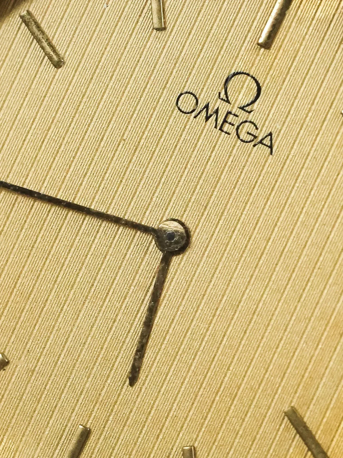 Omega vintage watch dial with textured gold finish and baton markers