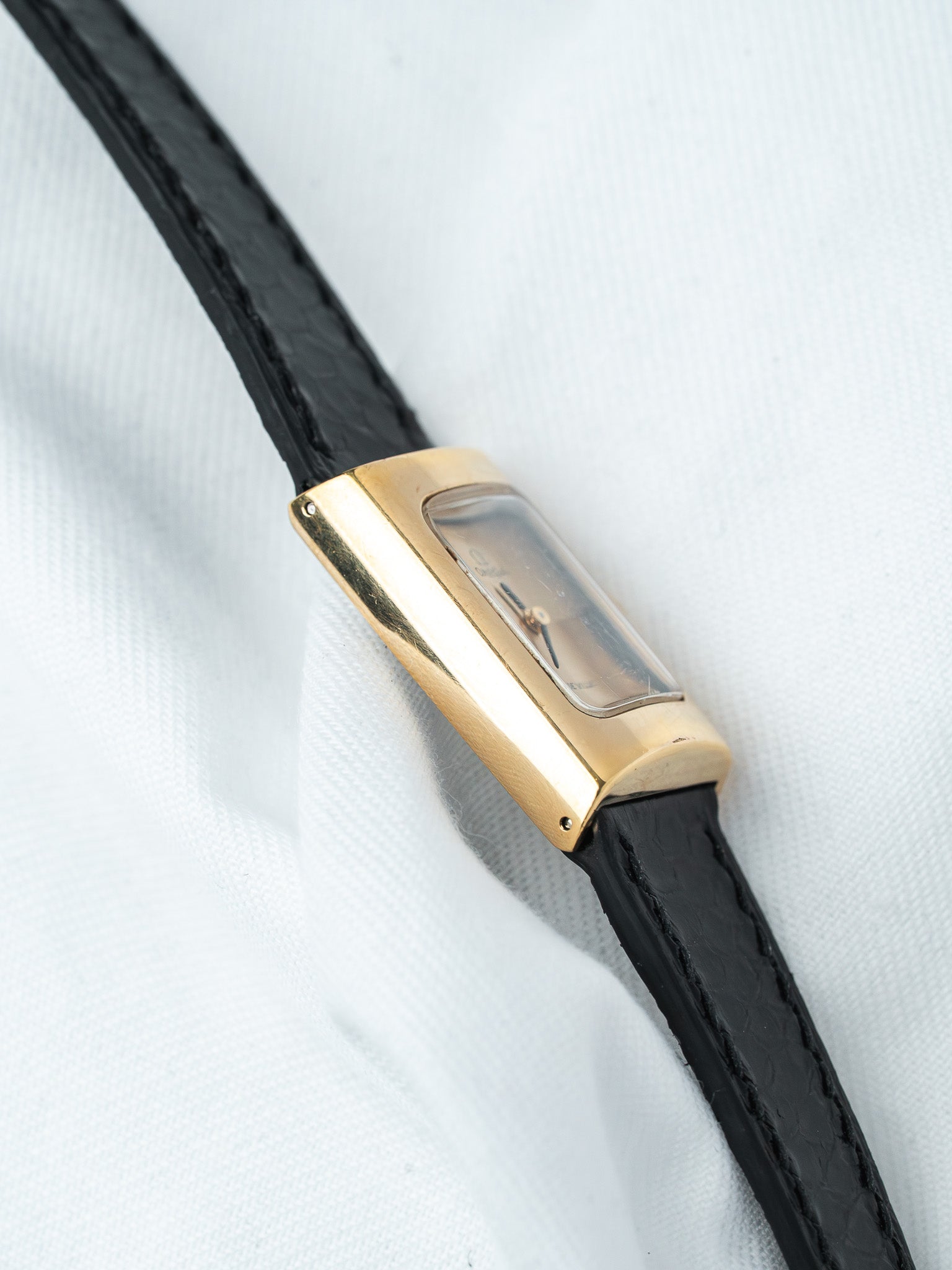 Cartier vintage watch with gold case, black leather strap, and rectangular dial