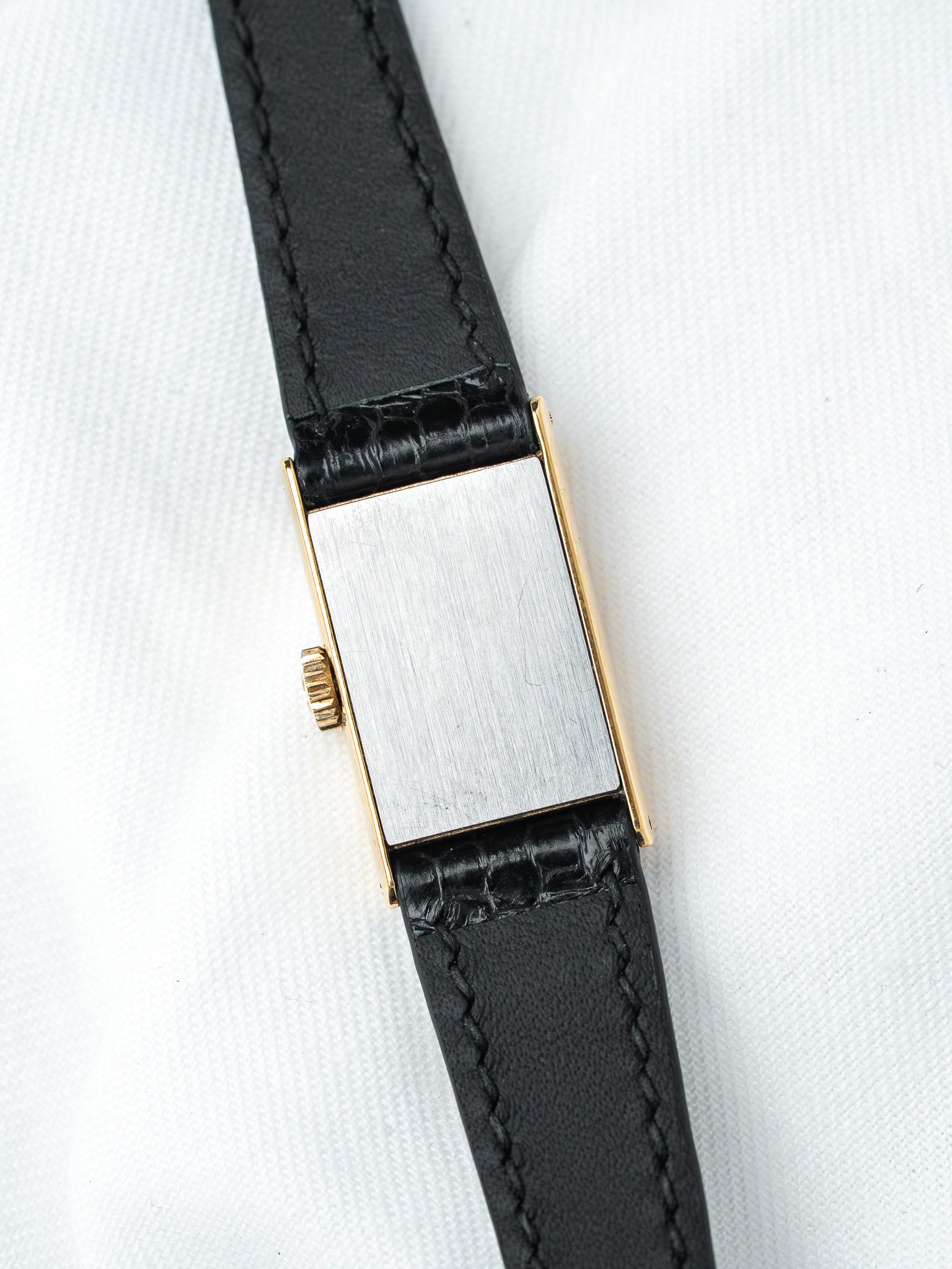 Vintage rectangular watch with gold case, brushed silver dial, black leather strap