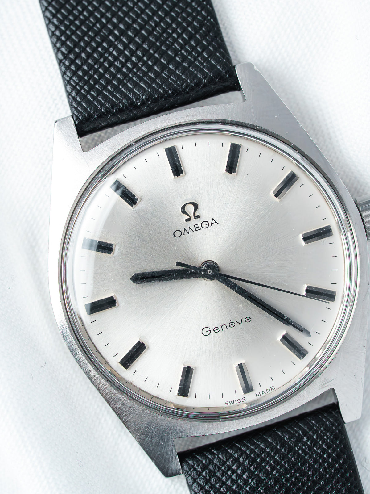 Omega Genève vintage watch with silver dial, black markers, and textured black strap