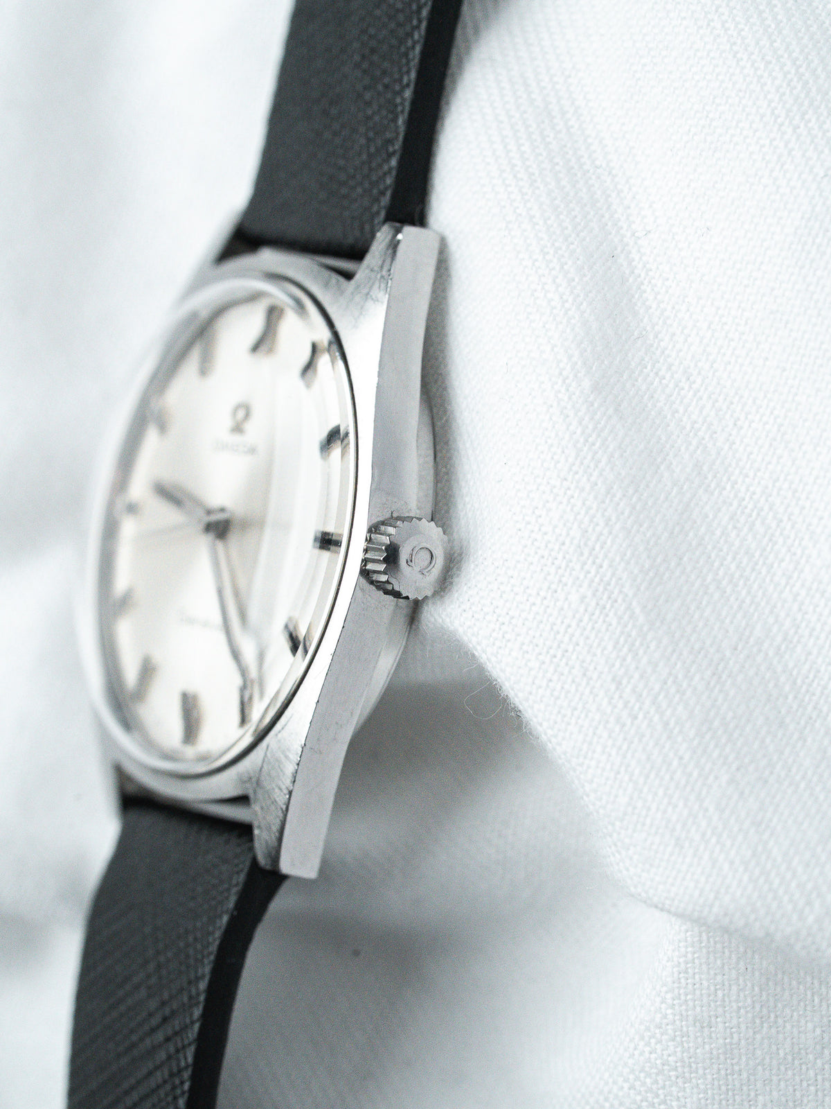 Vintage Omega watch with white dial, black strap, and stainless steel case