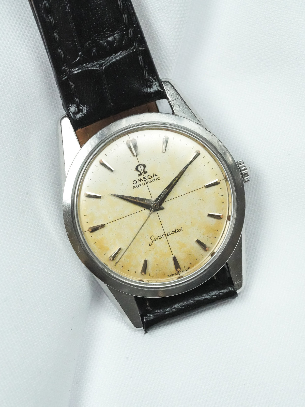 Vintage Omega Seamaster automatic watch with cream dial, steel case, black leather strap on white background